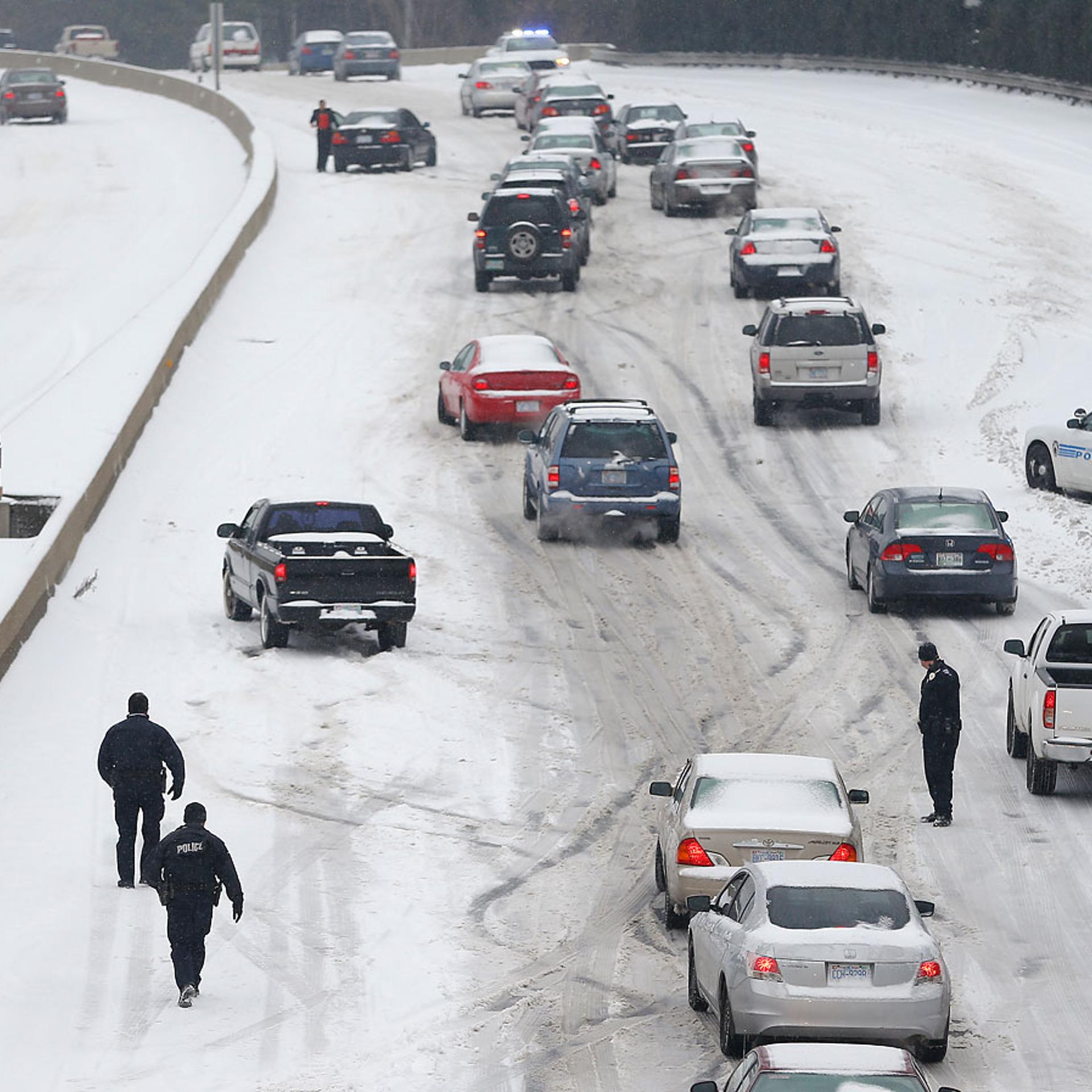 Charlotte Mecklenburg Police Officers work to assist motorists as they attempt to drive up a hill that is covered in snow in Charlotte