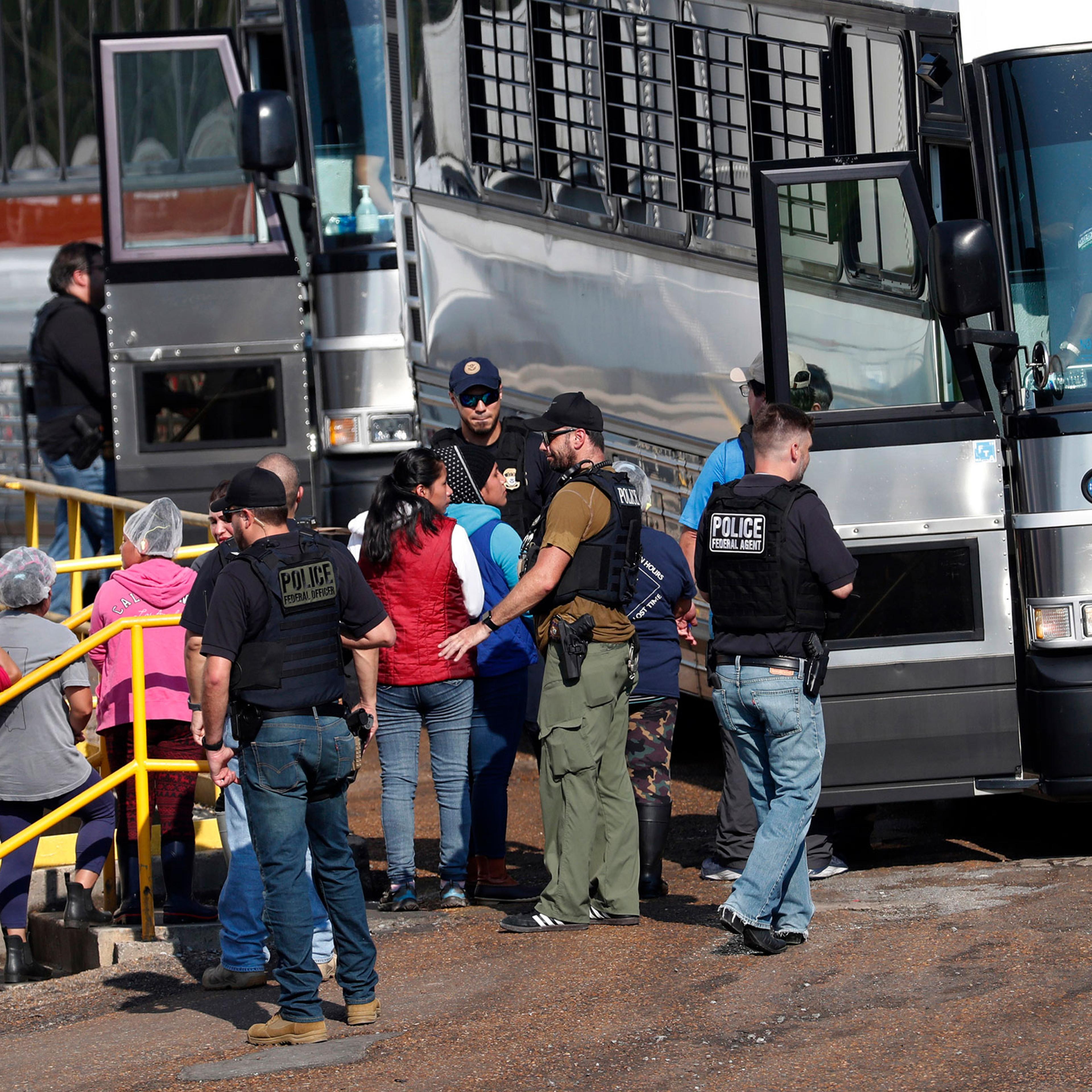 Handcuffed workers are escorted into a bus for transportation to a processing center following a raid by U.S. immigration officials at a Koch Foods Inc., plant in Morton, Miss. on Aug. 7, 2019.