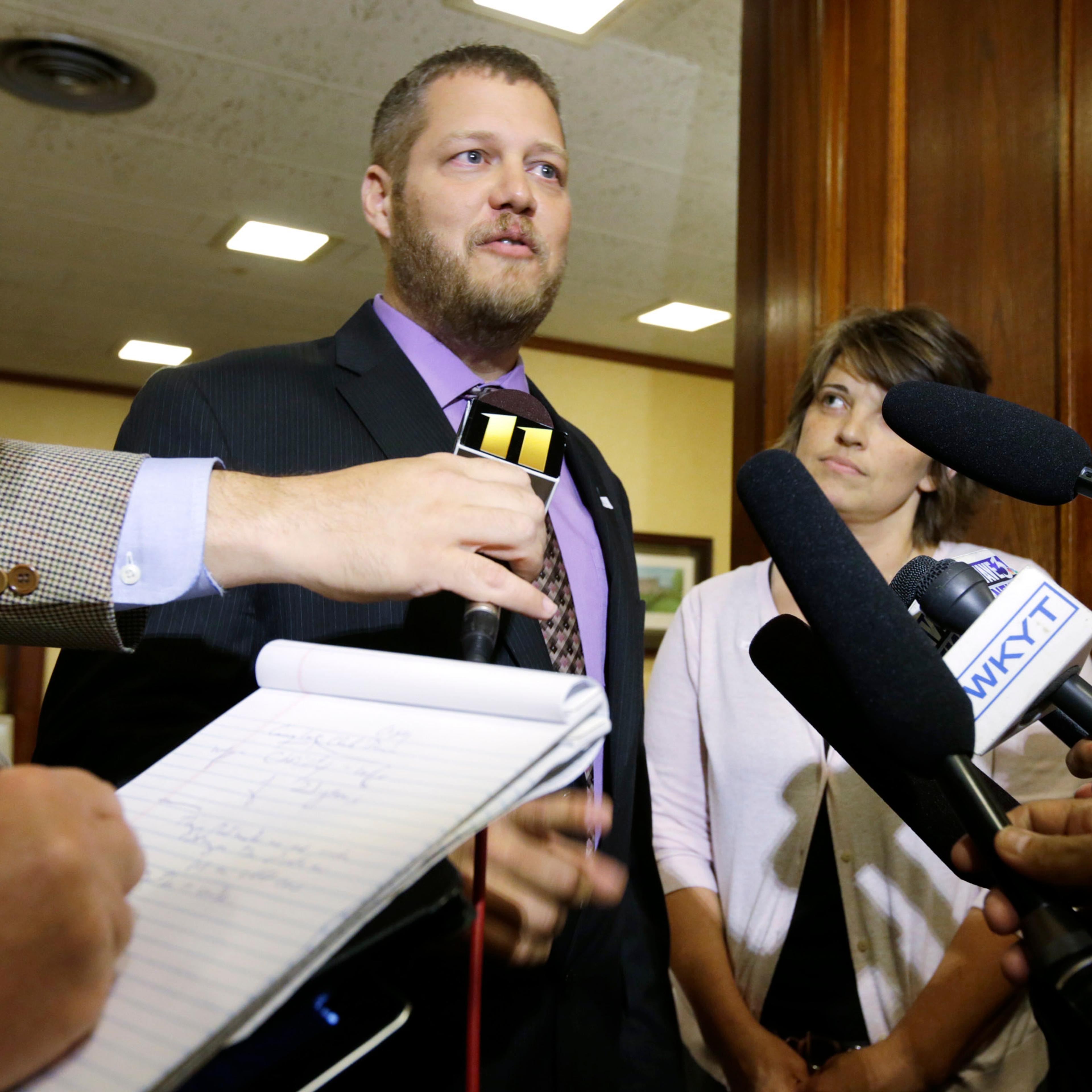 County Clerk Casey Davis (C), with wife Christy Davis (R), speak to the media before a meeting with Gov. Steve Beshear in Frankfort, Ky., on July 9, 2015.