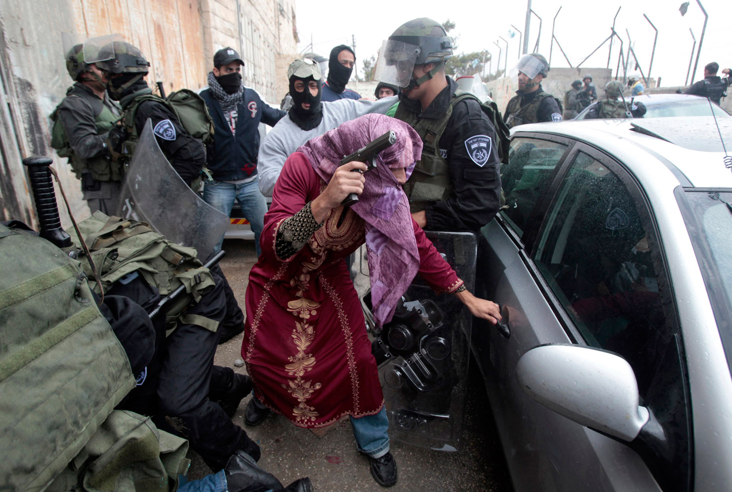 An undercover Israeli policeman dressed as a Palestinian woman opens a car door in the Shuafat refugee camp.