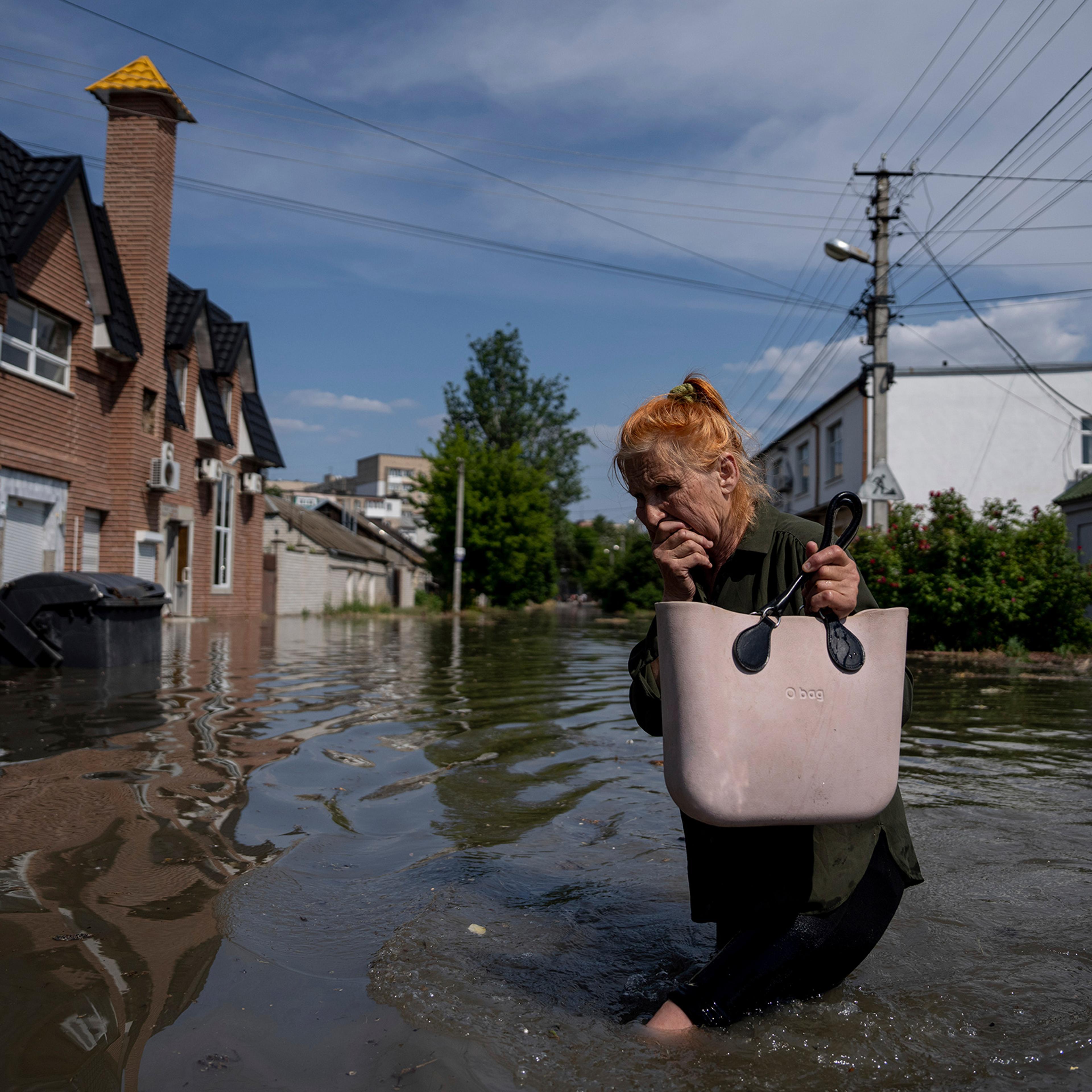 A local resident makes her way through a flooded road after the walls of the Kakhovka dam collapsed overnight, in Kherson, Ukraine, on Jun 6.