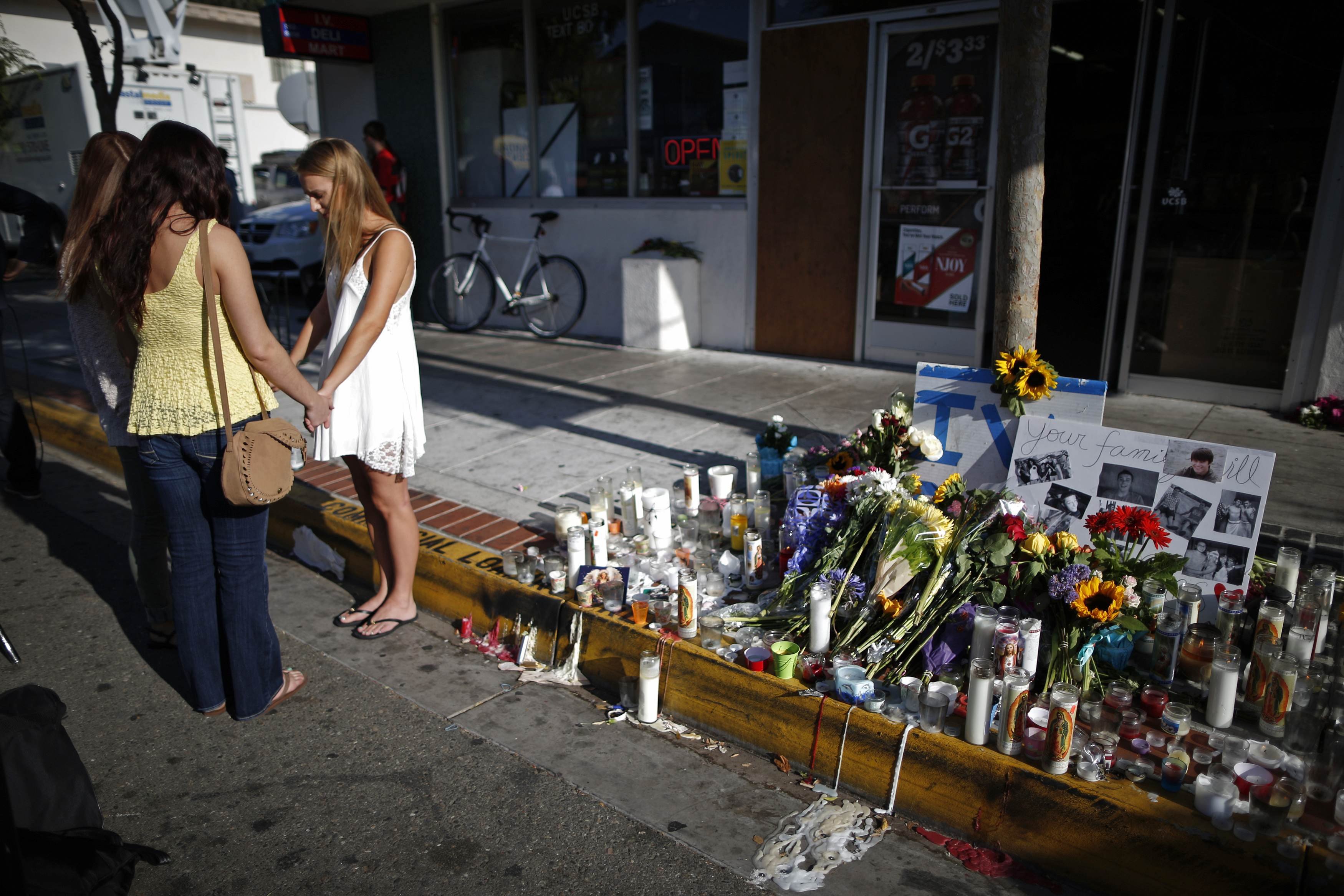 Women pray in front of a makeshift memorial for UCSB student Christopher Michael-Martinez in Isla Vista