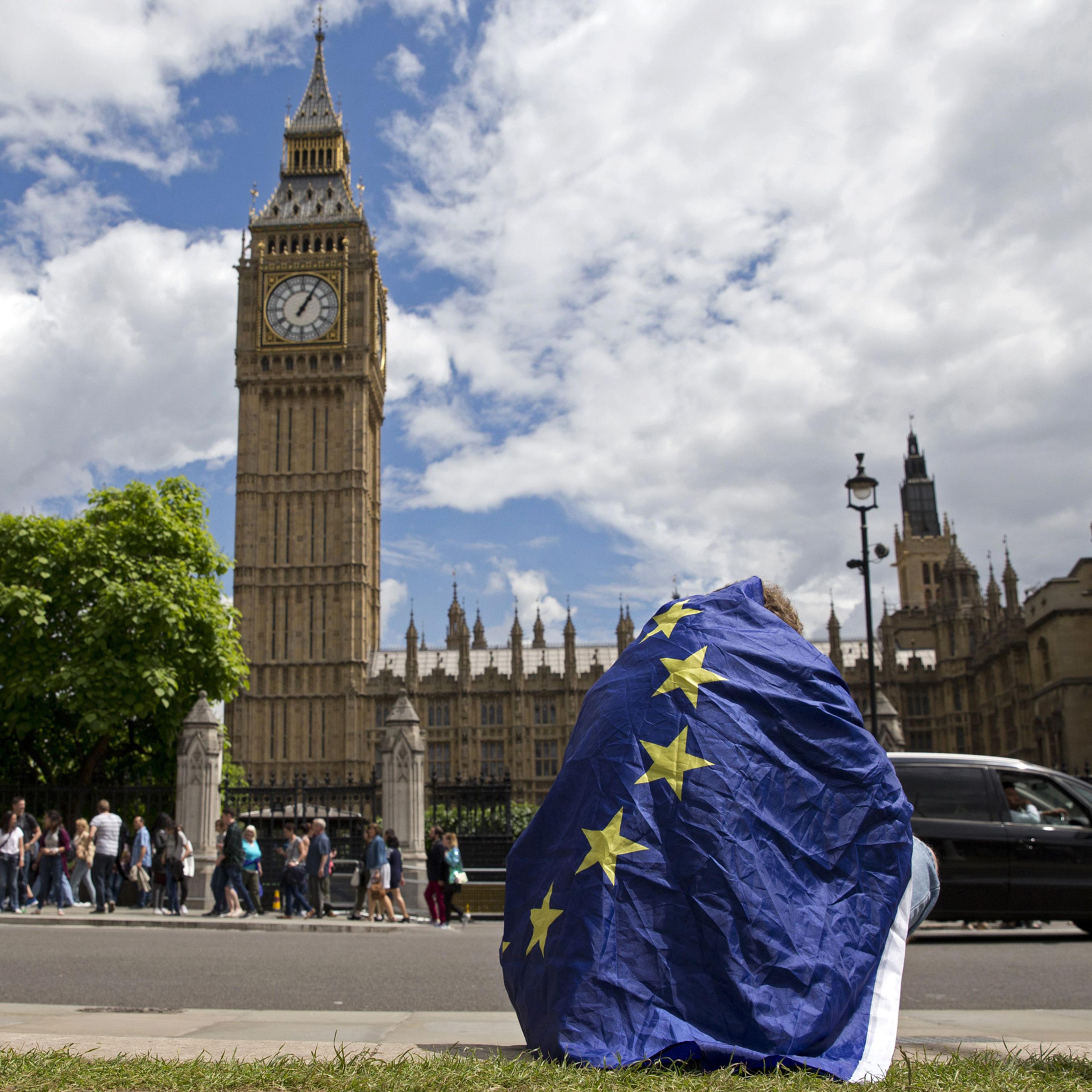TOPSHOT - A demonstrator draped in an EU flag sits on floor during a protest against the outcome of the UK's June 23 referendum on the European Union (EU), in central London on June 25, 2016. The result of Britain's June 23 referendum vote to leave the E