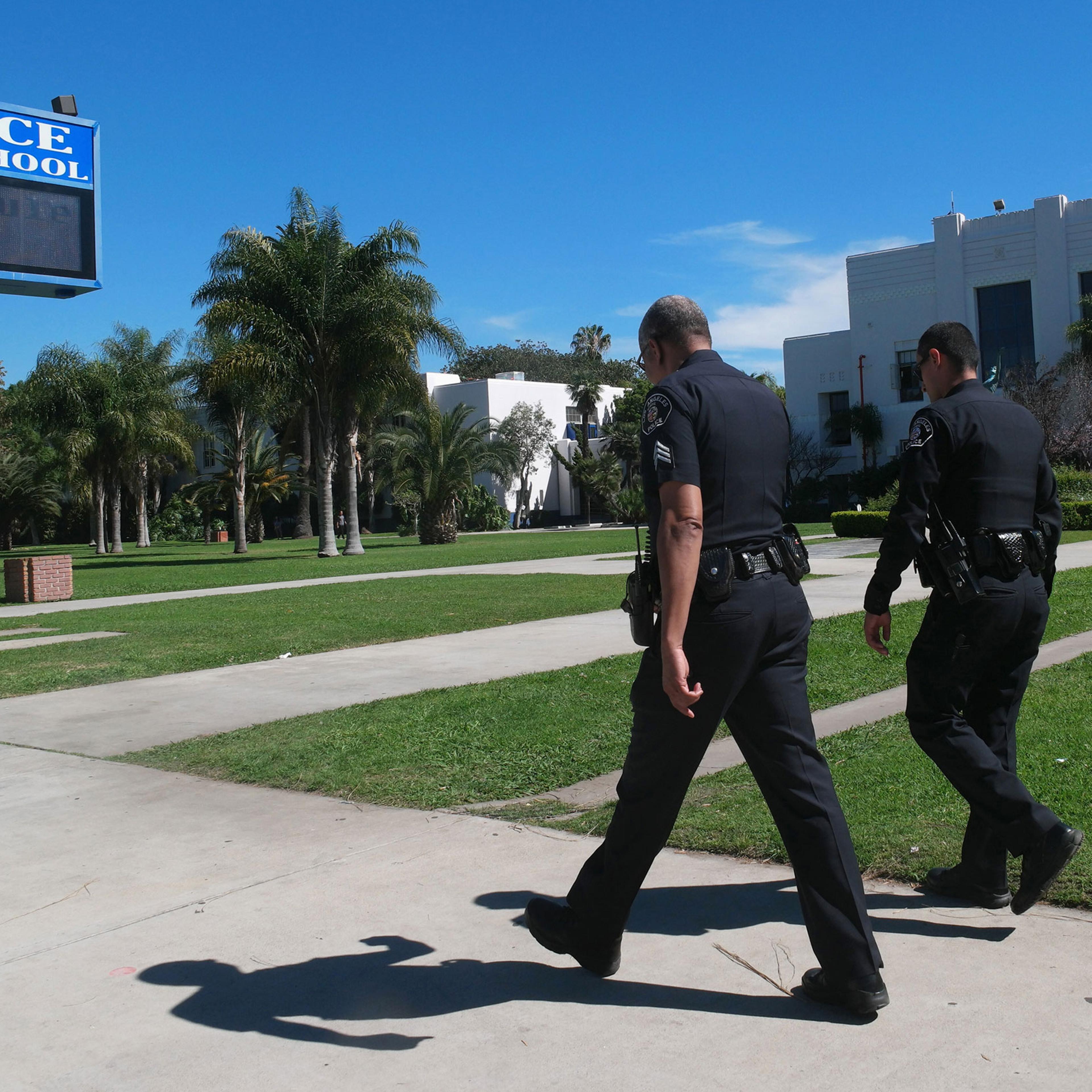 Police officers walk in front of Venice High School where they are investigating allegations of sexual assault in Los Angeles
