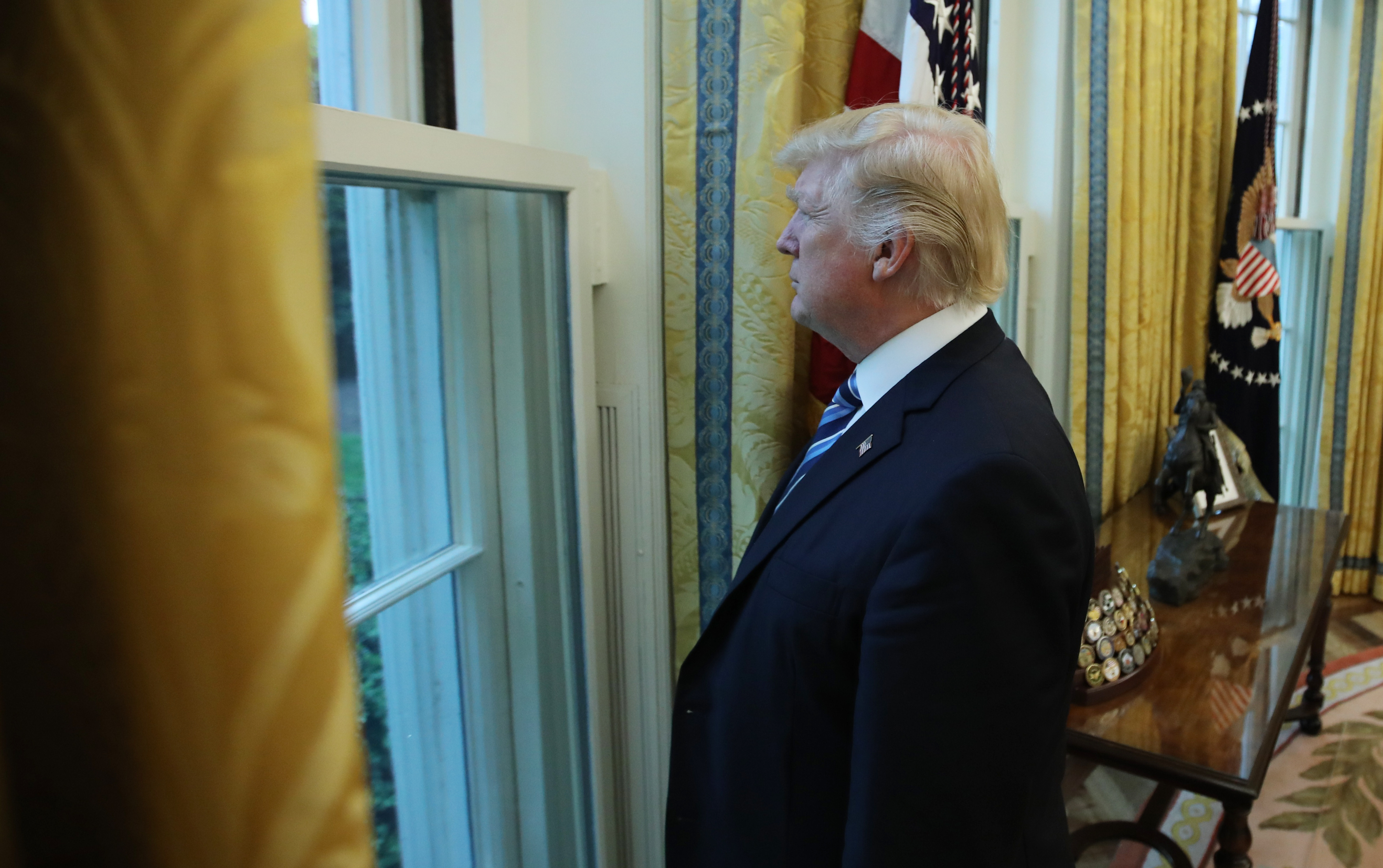 U.S. President Donald Trump looks out window of the Oval Office following an interview with Reuters at the White House in Washington