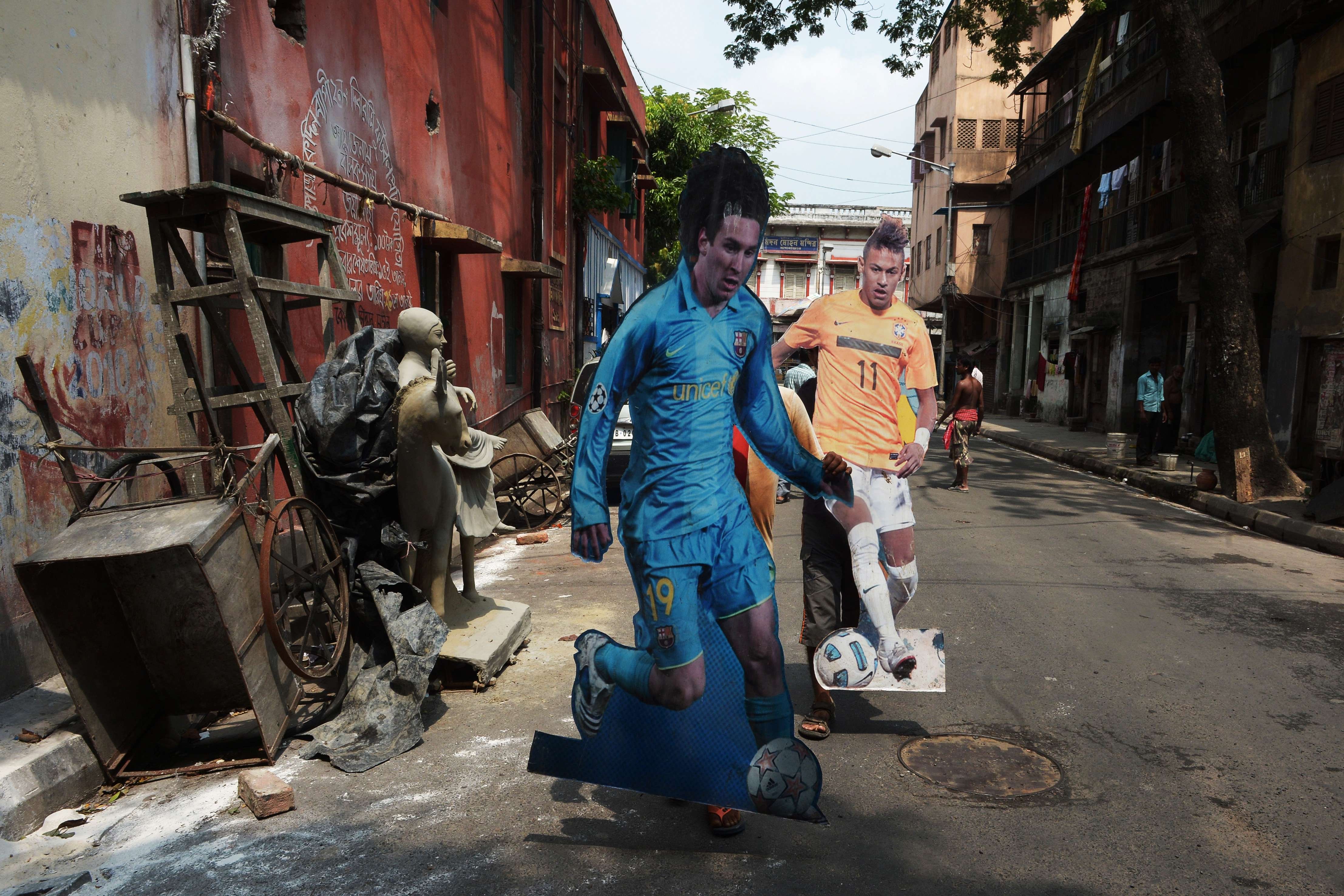 Local Indian footballers carry cutout portraits of Brazilian soccer player Neymar and Argentine soccer player Lionel Messi to a local football club in Kolkata on June 9, 2014.