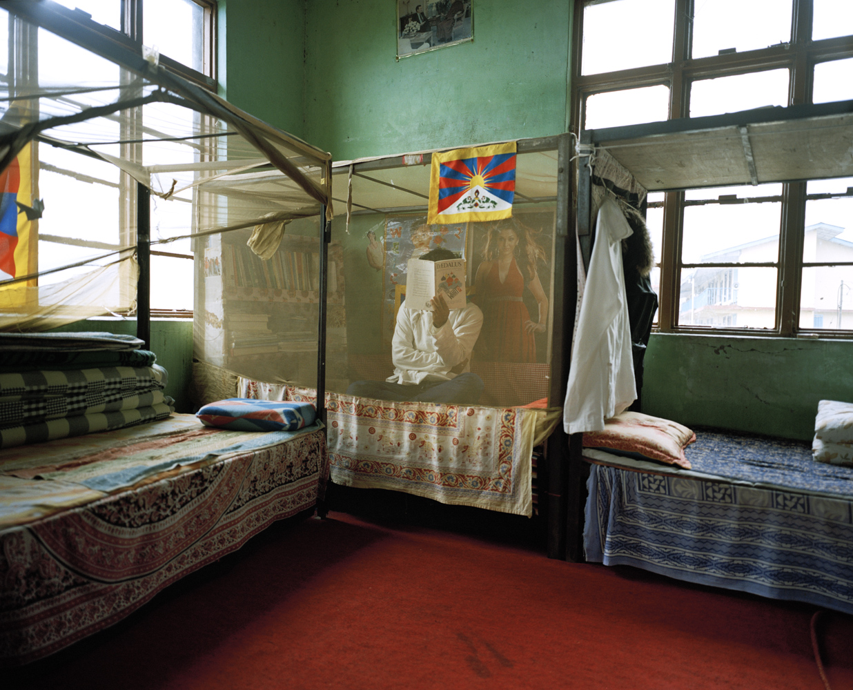 A student conceals his face on his bed inside the men's dormitory at the Tibetan Transit School.