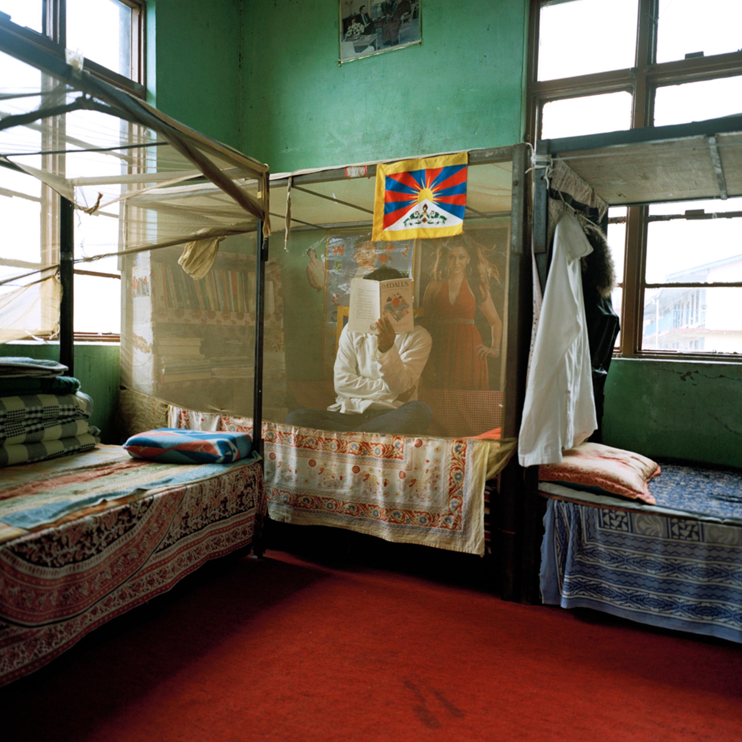 A student conceals his face on his bed inside the men's dormitory at the Tibetan Transit School.