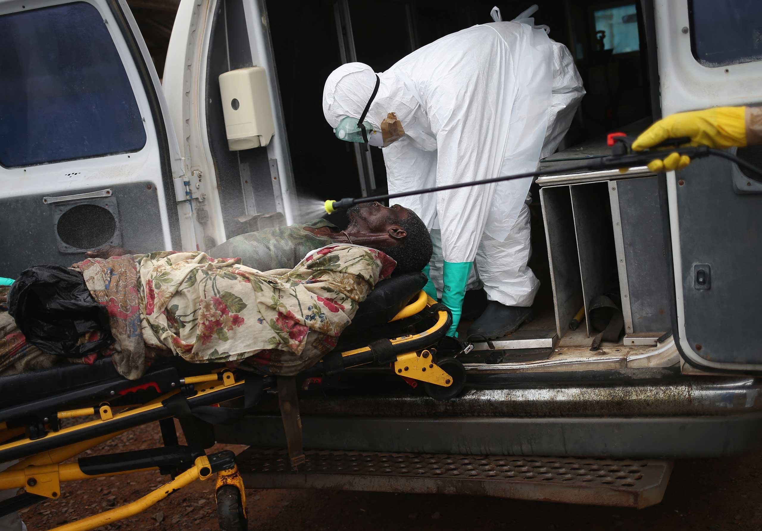 A burial team disinfects an Ebola victim while collecting him for cremation on Oct. 2, 2014 in Monrovia, Liberia.