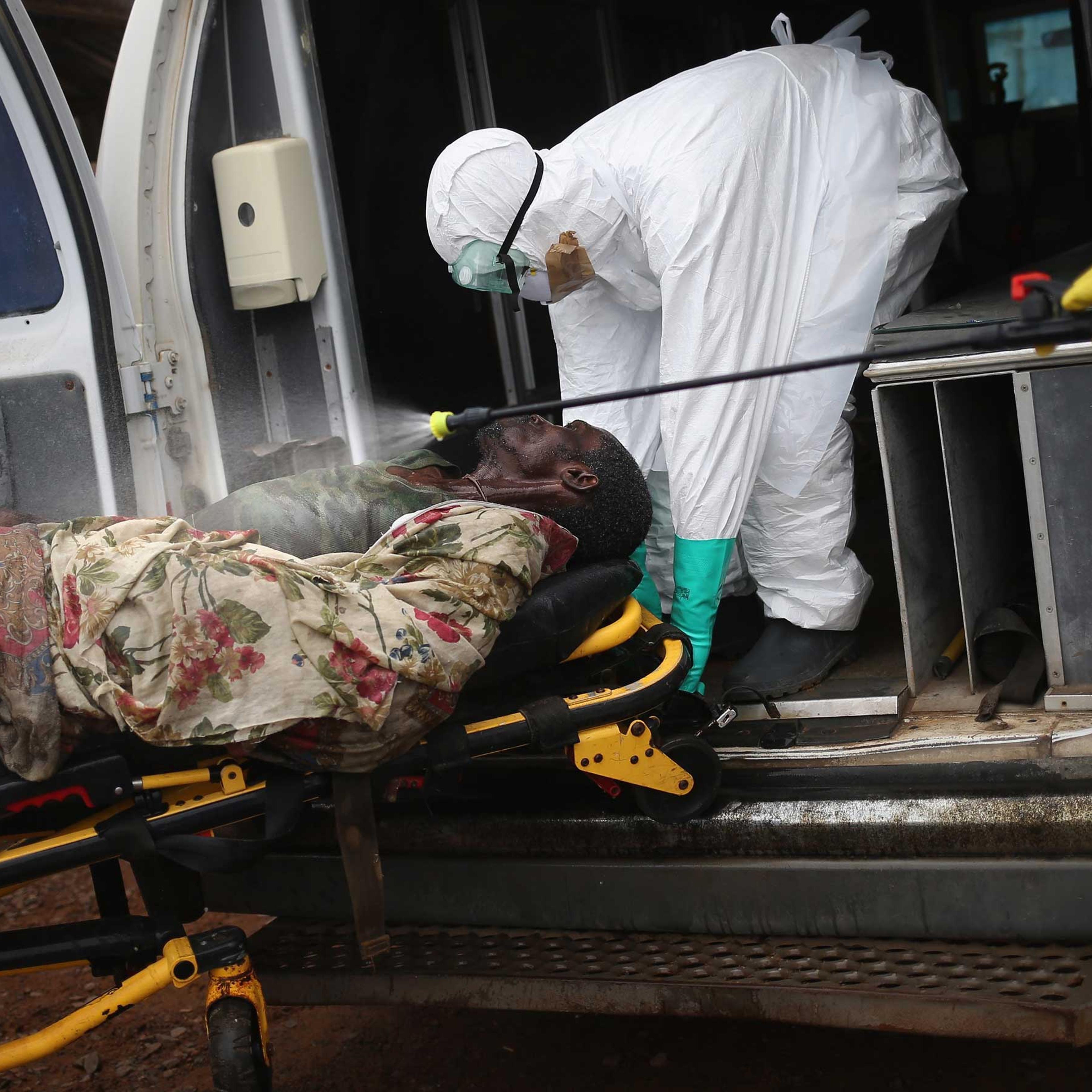 A burial team disinfects an Ebola victim while collecting him for cremation on Oct. 2, 2014 in Monrovia, Liberia.