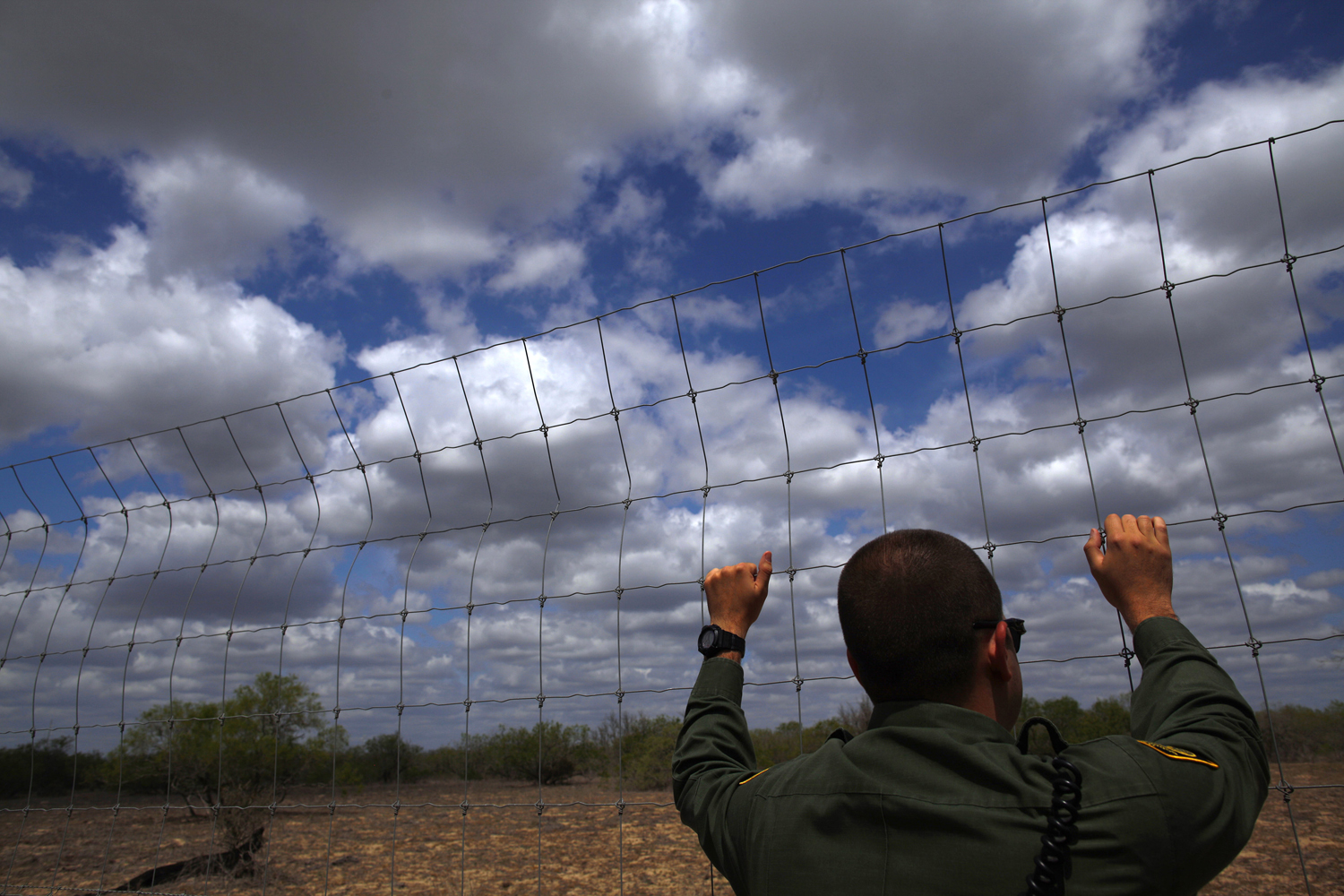 A U.S. Border Patrol agent looks out at the desert near Falfurrias, Texas