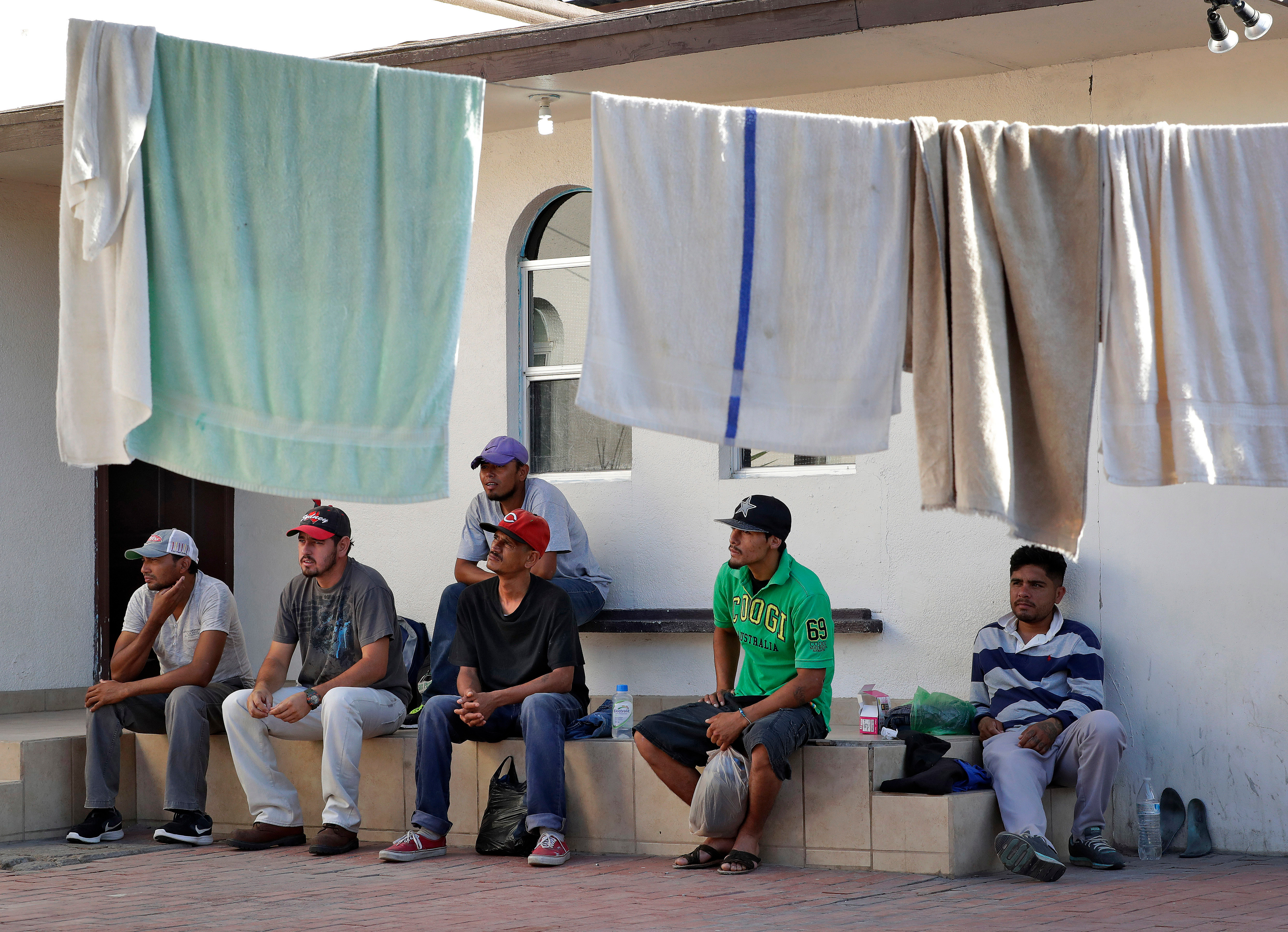 Men sit outside a home with laundry hanging to dry