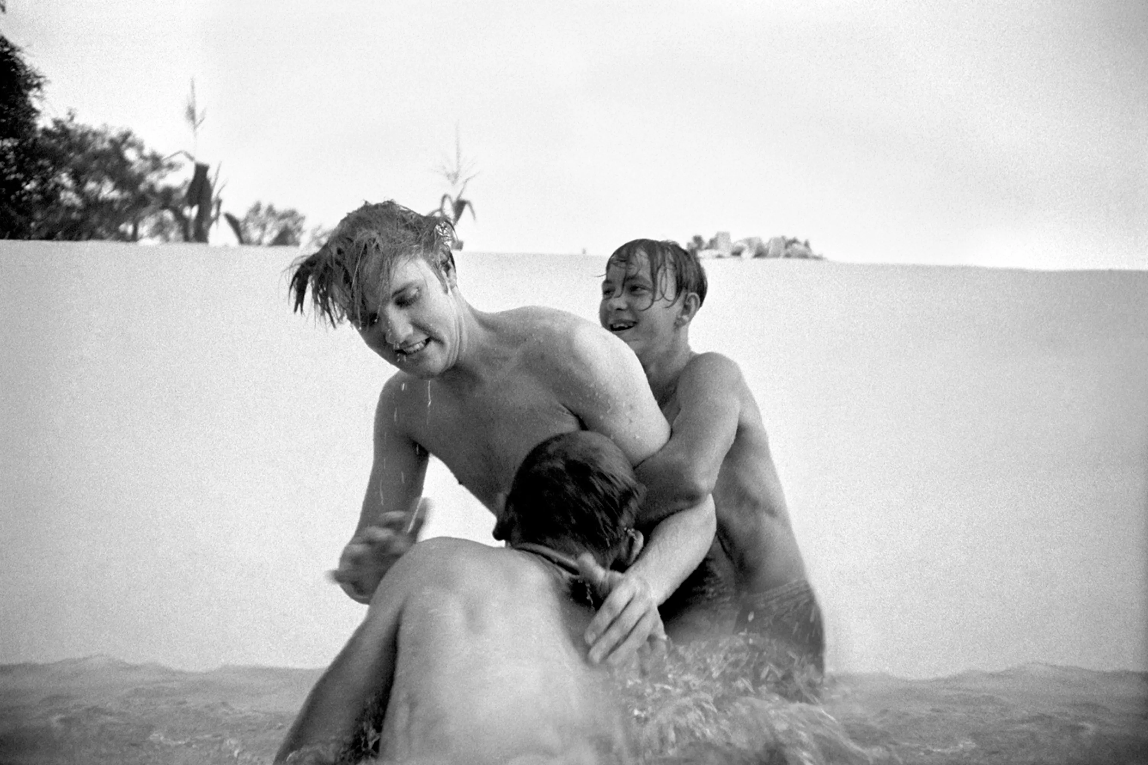 July 4, 1956. 1034 Auburn Drive, Memphis. Elvis liked horseplay — he loved physical activity. Here he is with his cousins Billy Smith (behind) and Bobby Smith (foreground) horsing around in a half-filled swimming pool at home. The valve was broken so they couldn't fill it all. I could stand on the solid base of the pool and shoot at their level.