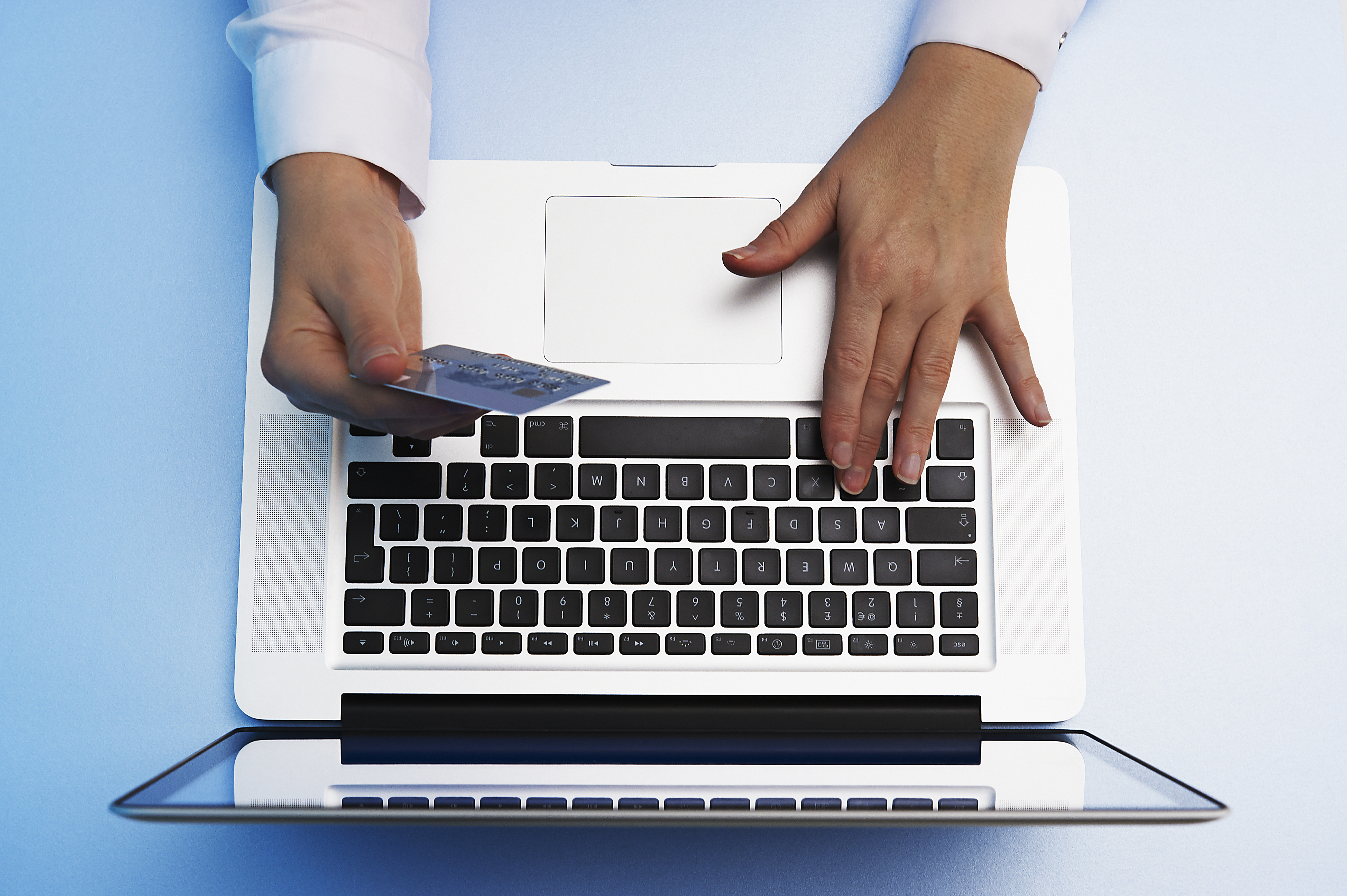 overhead view of hand holding credit card and using laptop