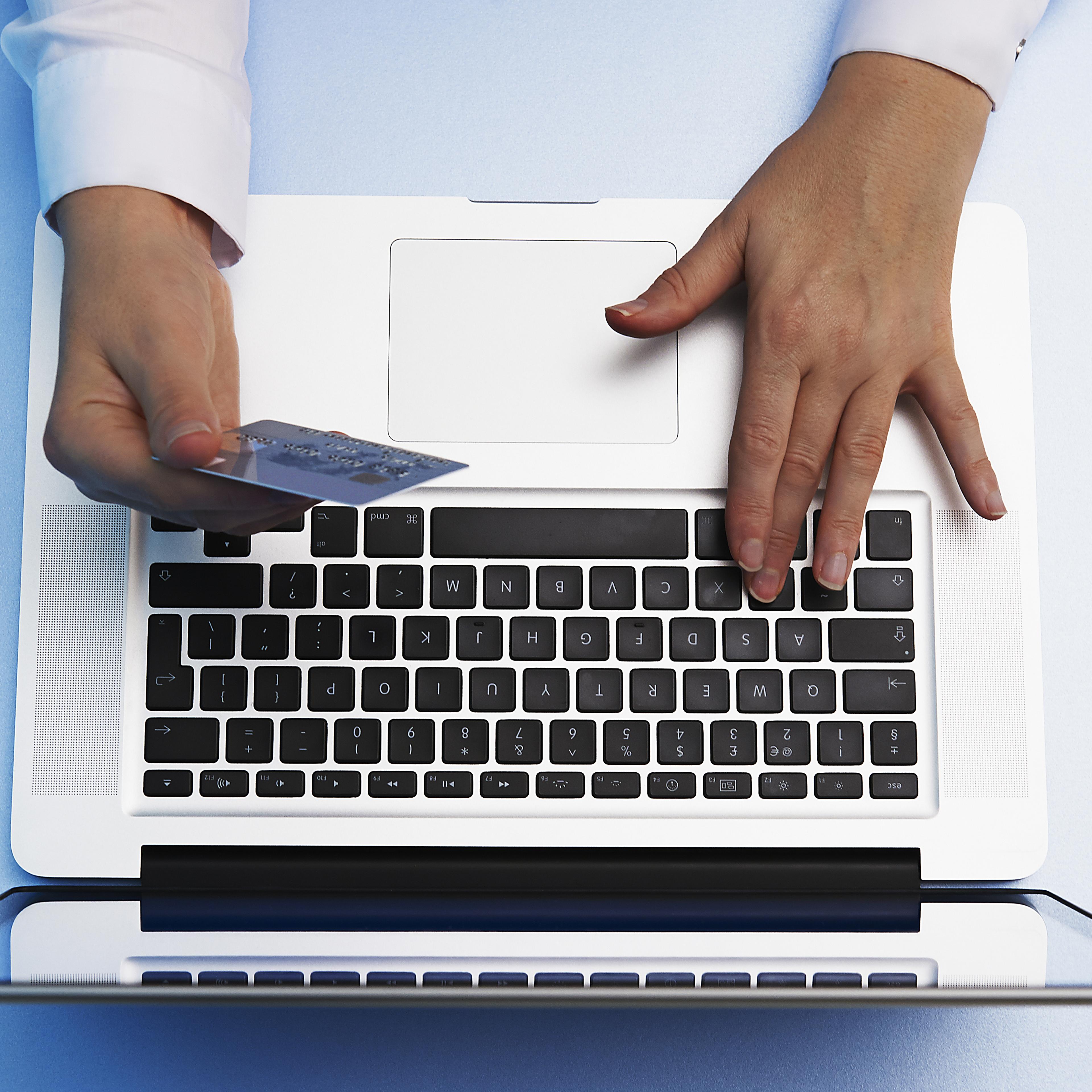overhead view of hand holding credit card and using laptop