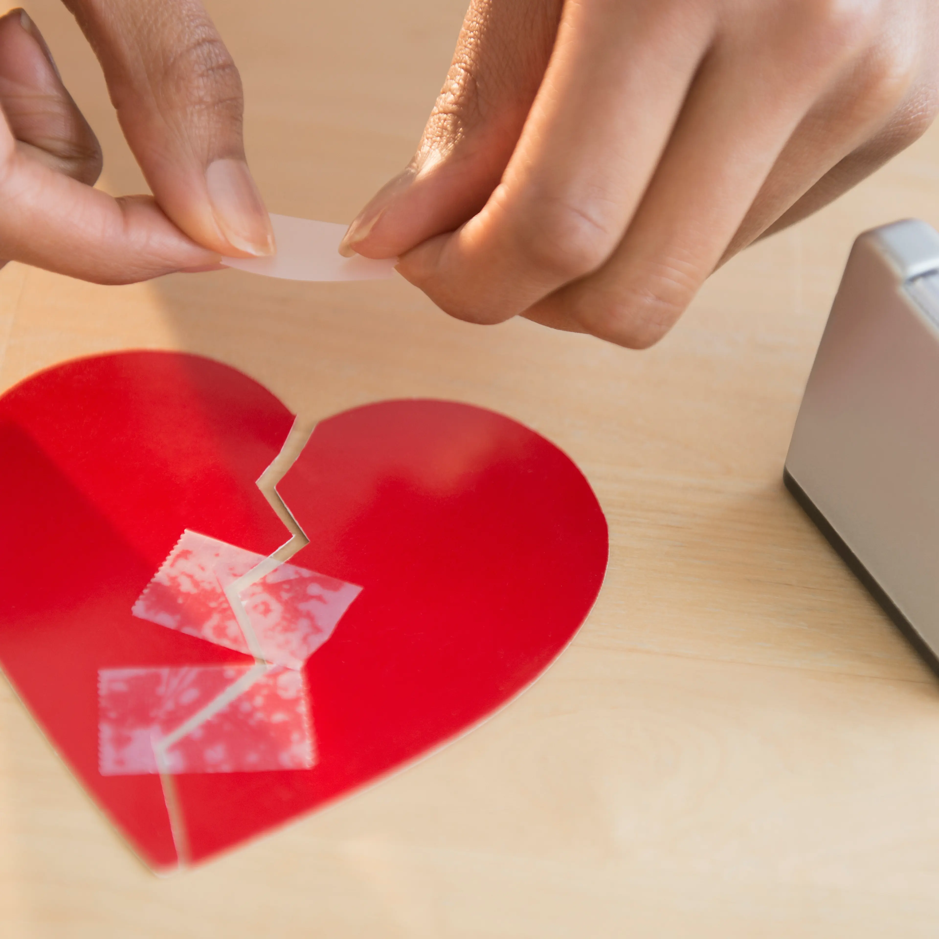 Mixed race woman taking broken paper heart