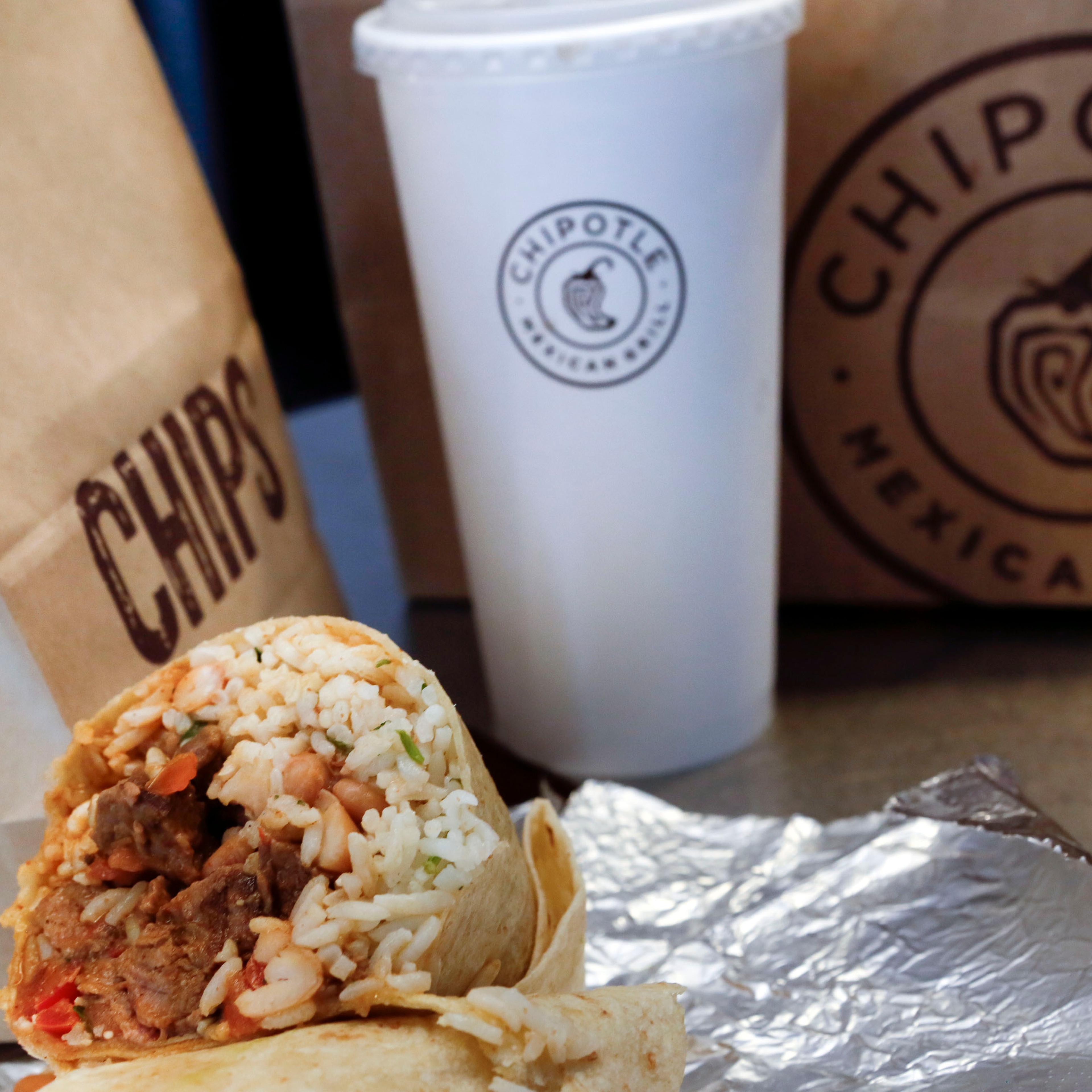 A steak burrito is arranged for a photograph with a drink and bags of chips at a Chipotle Mexican Grill Inc. restaurant in Hollywood, California, U.S., on Tuesday, July 16, 2013.