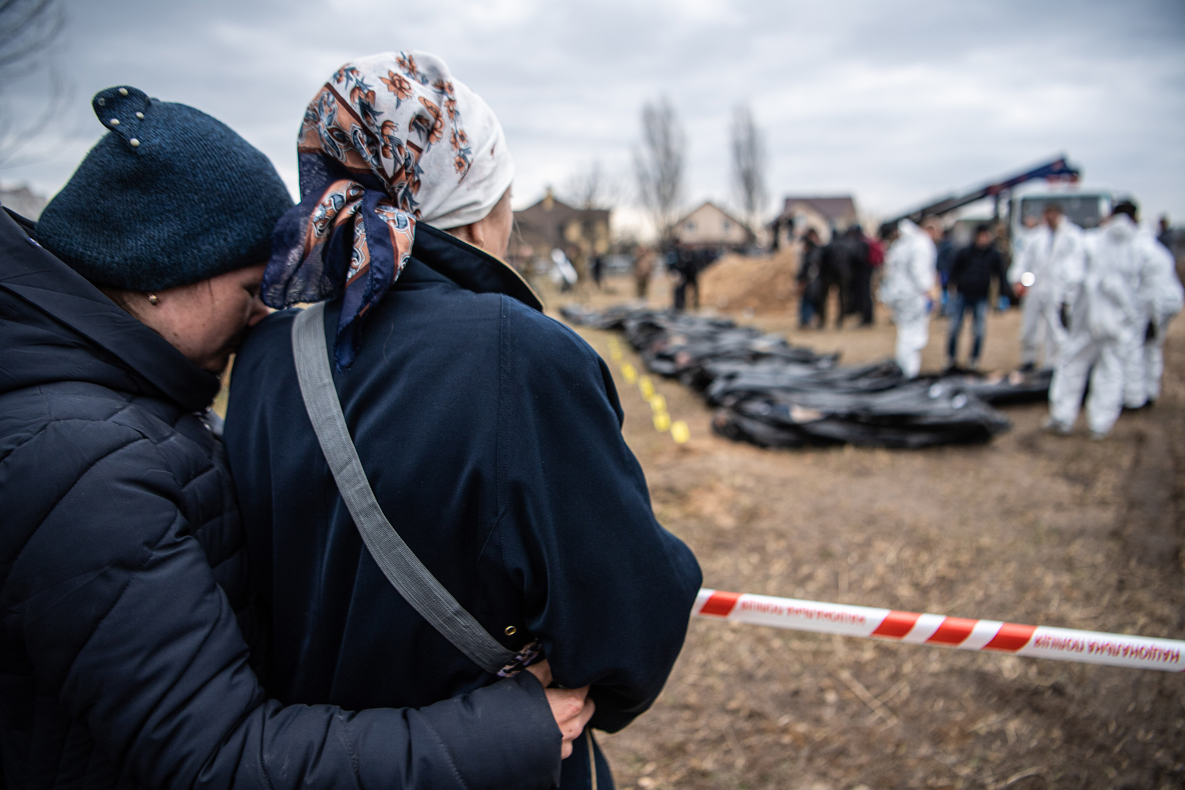 Women watch and embrace each other as bodies are exhumed from a mass grave and inspected by the authorities for possible war crimes in Bucha, April 8