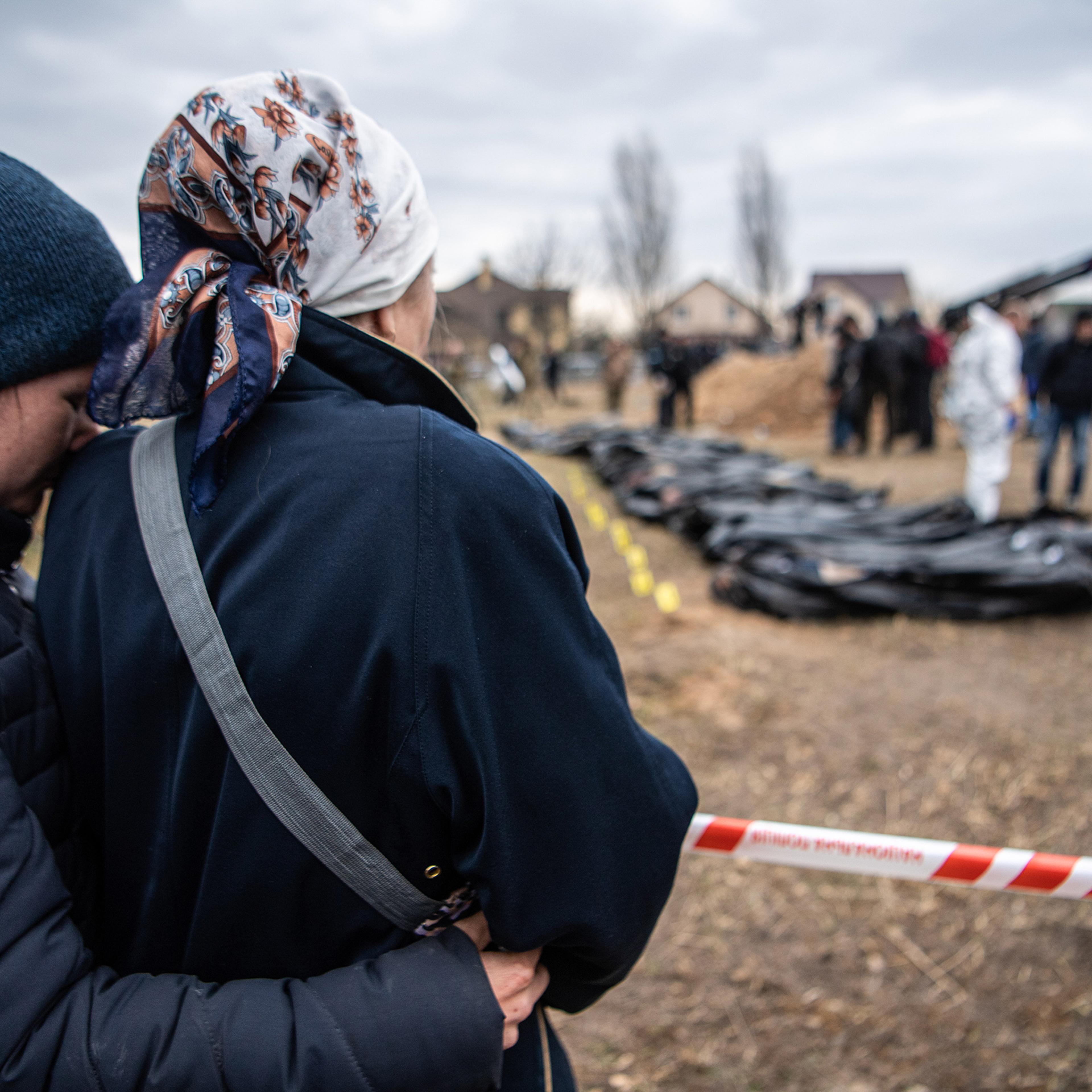 Women watch and embrace each other as bodies are exhumed from a mass grave and inspected by the authorities for possible war crimes in Bucha, April 8