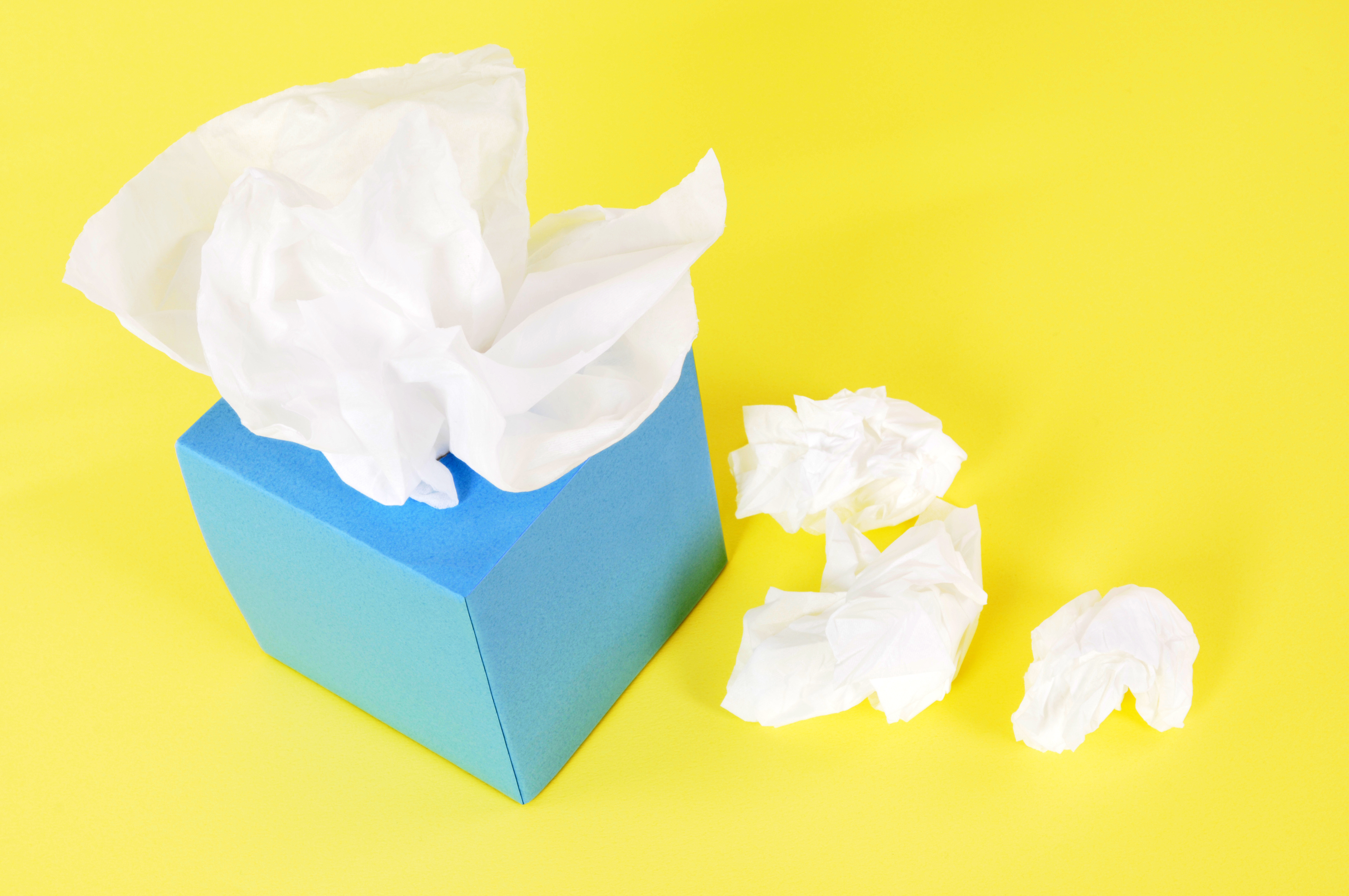 Blue tissue box with crumpled tissues beside it