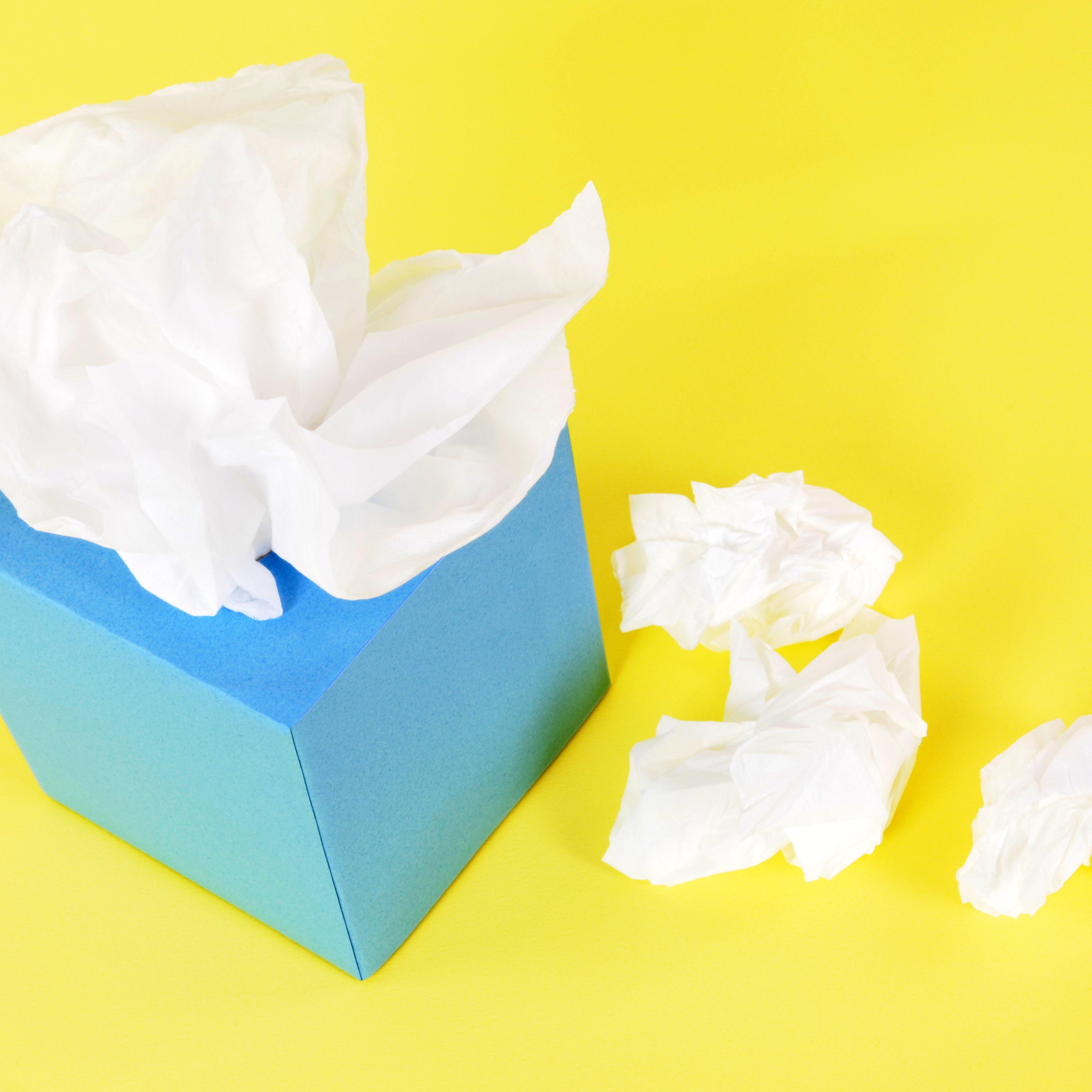 Blue tissue box with crumpled tissues beside it