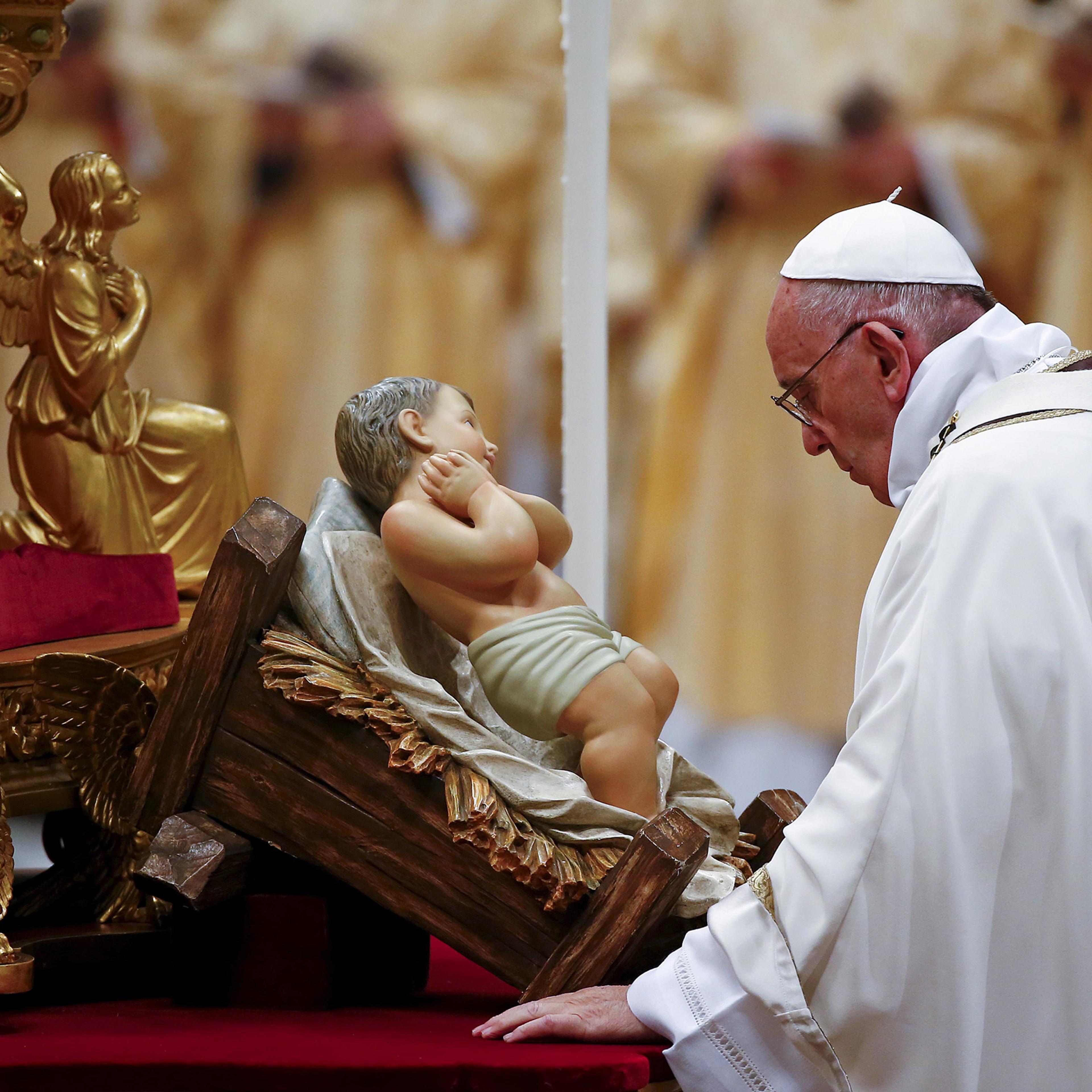 Pope Francis prays in front of a statue of baby Jesus as he leads the Christmas night Mass in Saint Peter's Basilica at the Vatican