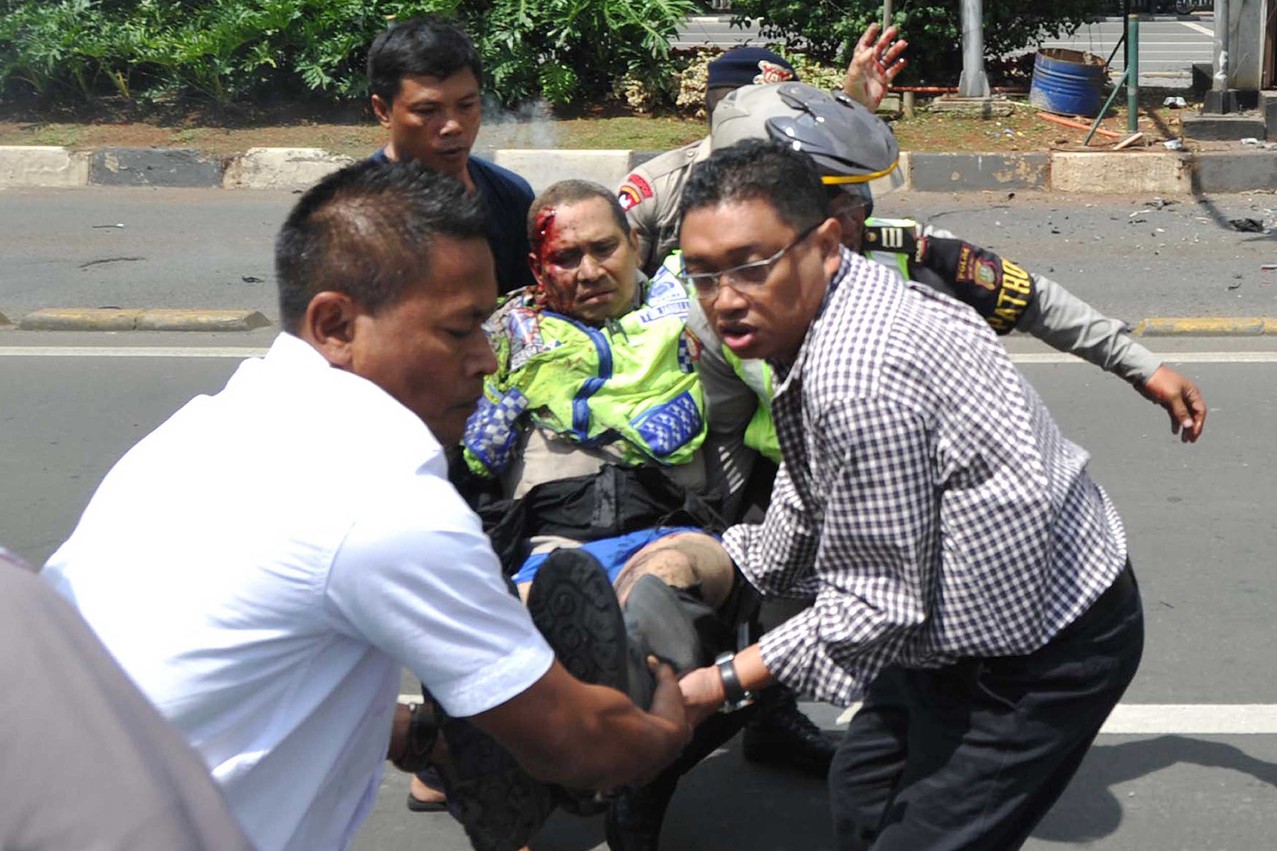 People carry an injured police officer near the site where an explosion went off at a police post in Jakarta, Indonesia, Jan. 14, 2016.