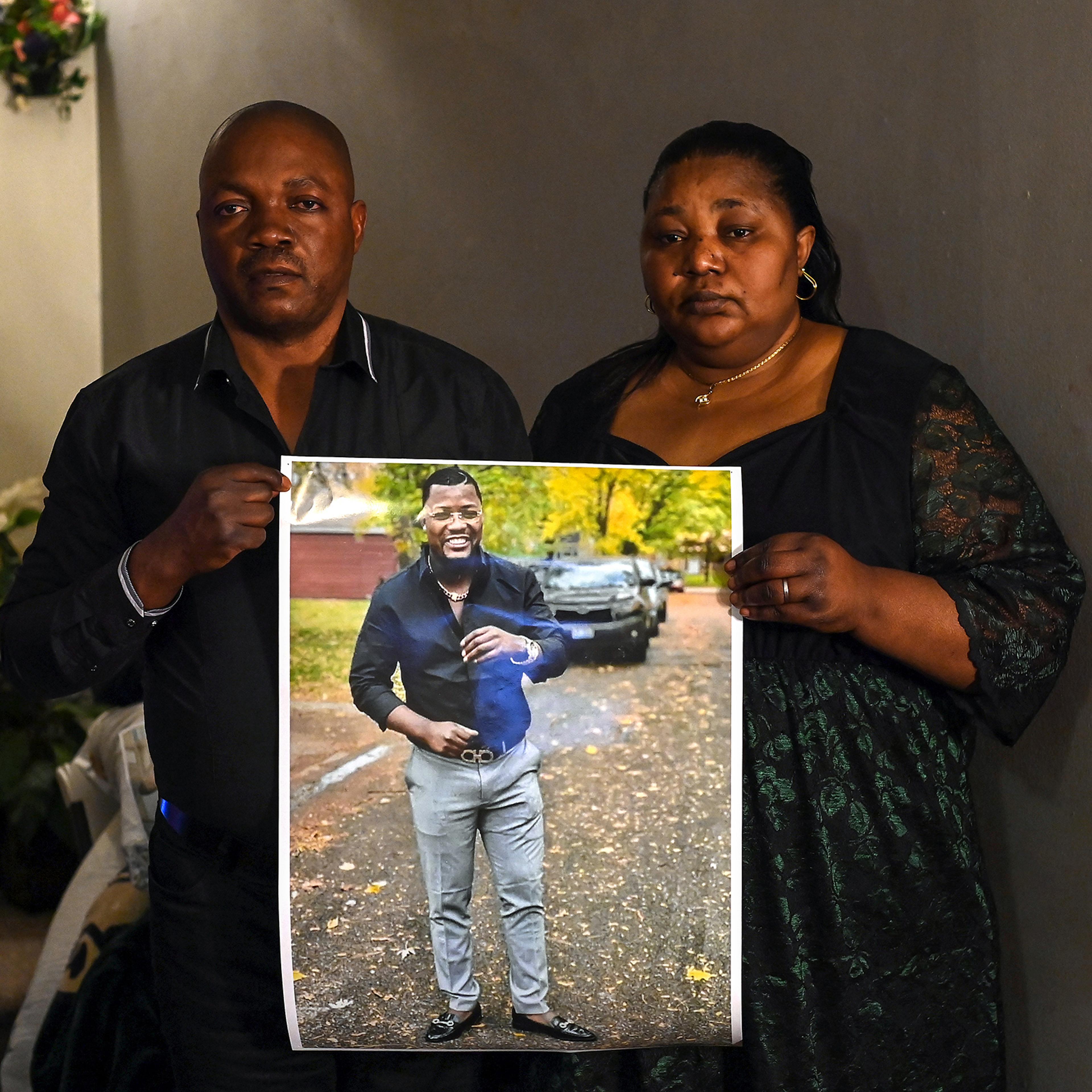 Patrick Lyoya's parents Peter Lyoya and Dorcas Lyoya pose for a portrait as they hold a photo of their son at their home on April 15, 2022 in Lansing, Mich.