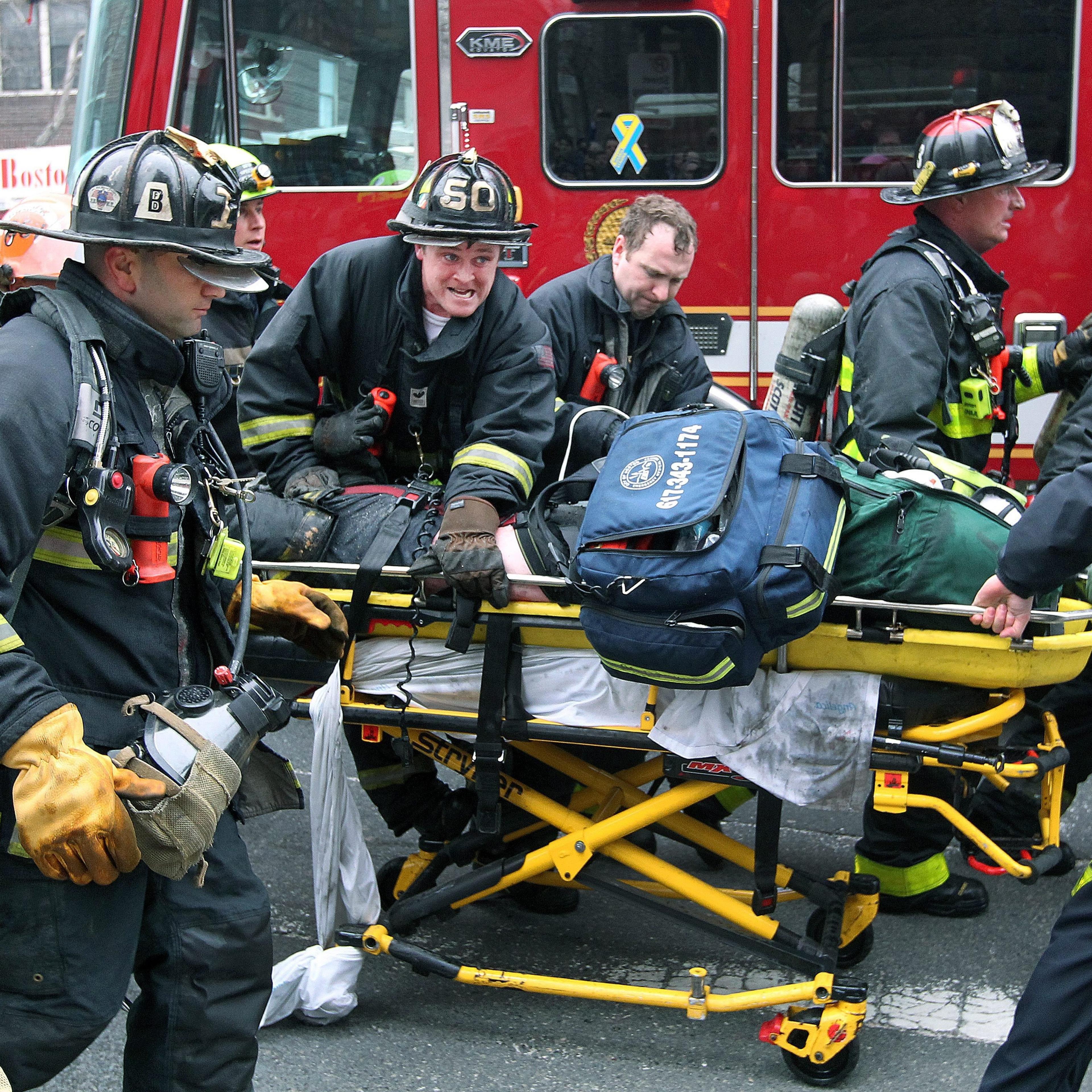 Boston Fire Department firefighters working on a fellow firefighter as he is rushed to an ambulance after being injured during a nine alarm fire in the Back Bay neighborhood of Boston, March 26, 2014.