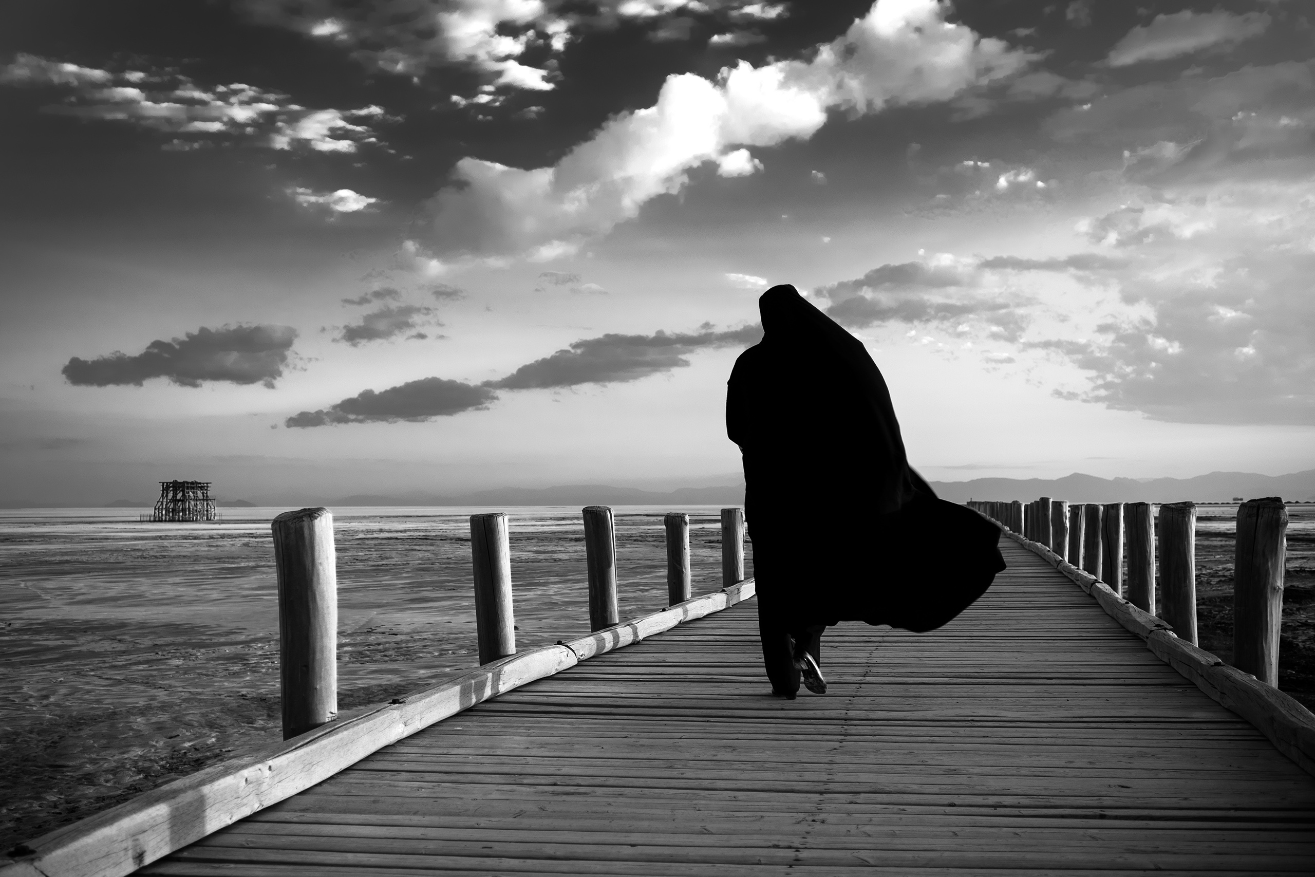 A woman walks on a wooden pier that once overlooked Lake Urmia's deep waters, July 2016, northwestern Iran. Since 1996, drought has contributed to the decline of the lake which now now covers only about 10 percent of the area it covered in the 1970s, Jul