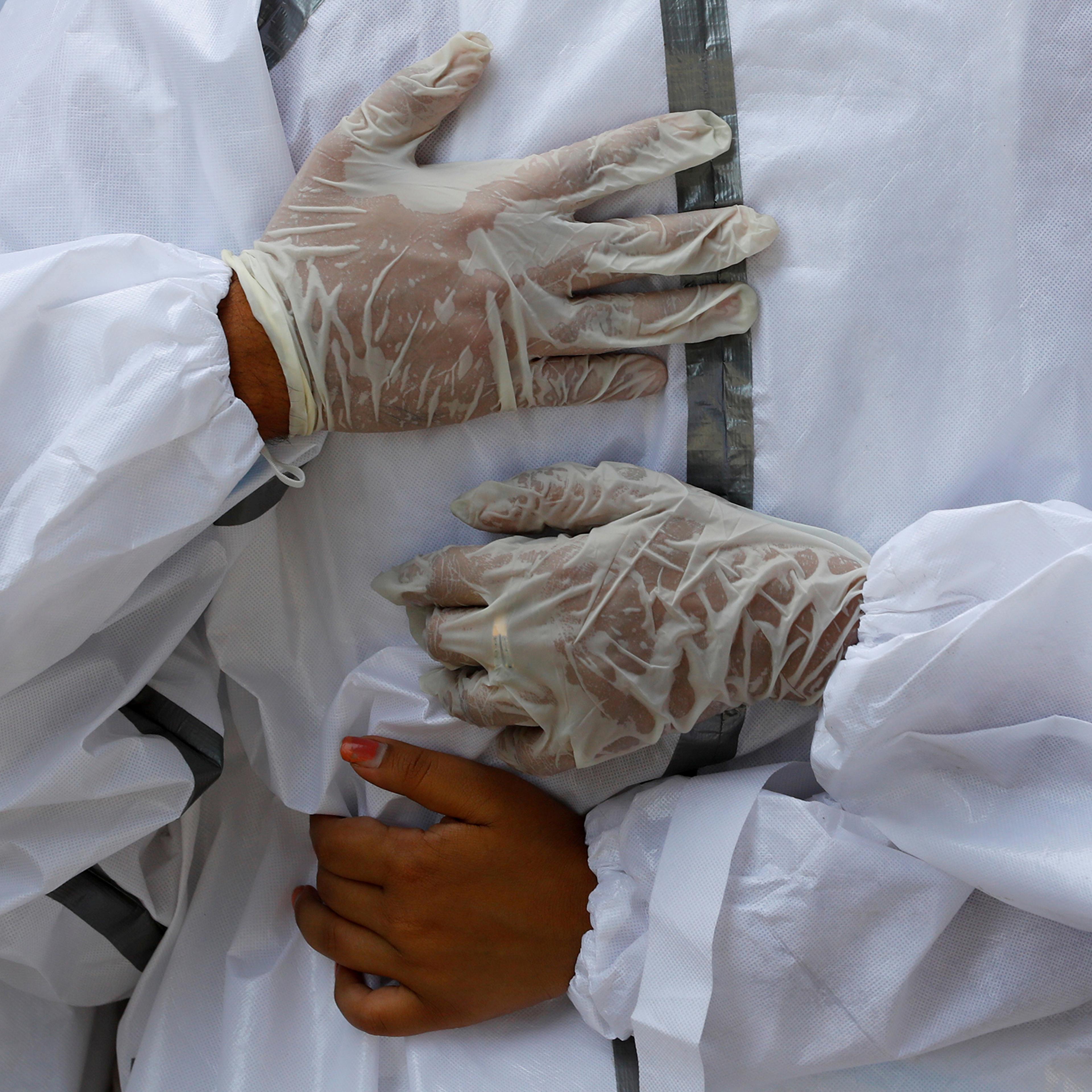 Relatives wearing personal protective equipment mourn a man who died from COVID-19 during his funeral at a crematorium in New Delhi on April 21