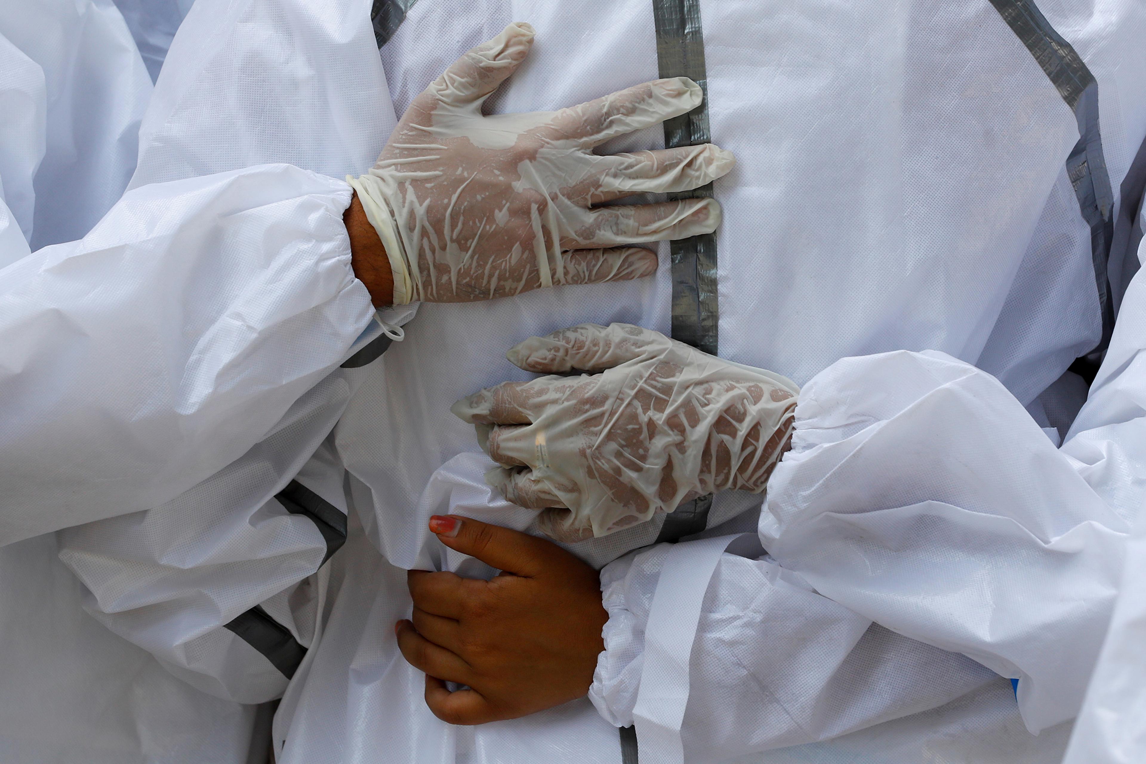 Relatives wearing personal protective equipment mourn a man who died from COVID-19 during his funeral at a crematorium in New Delhi on April 21