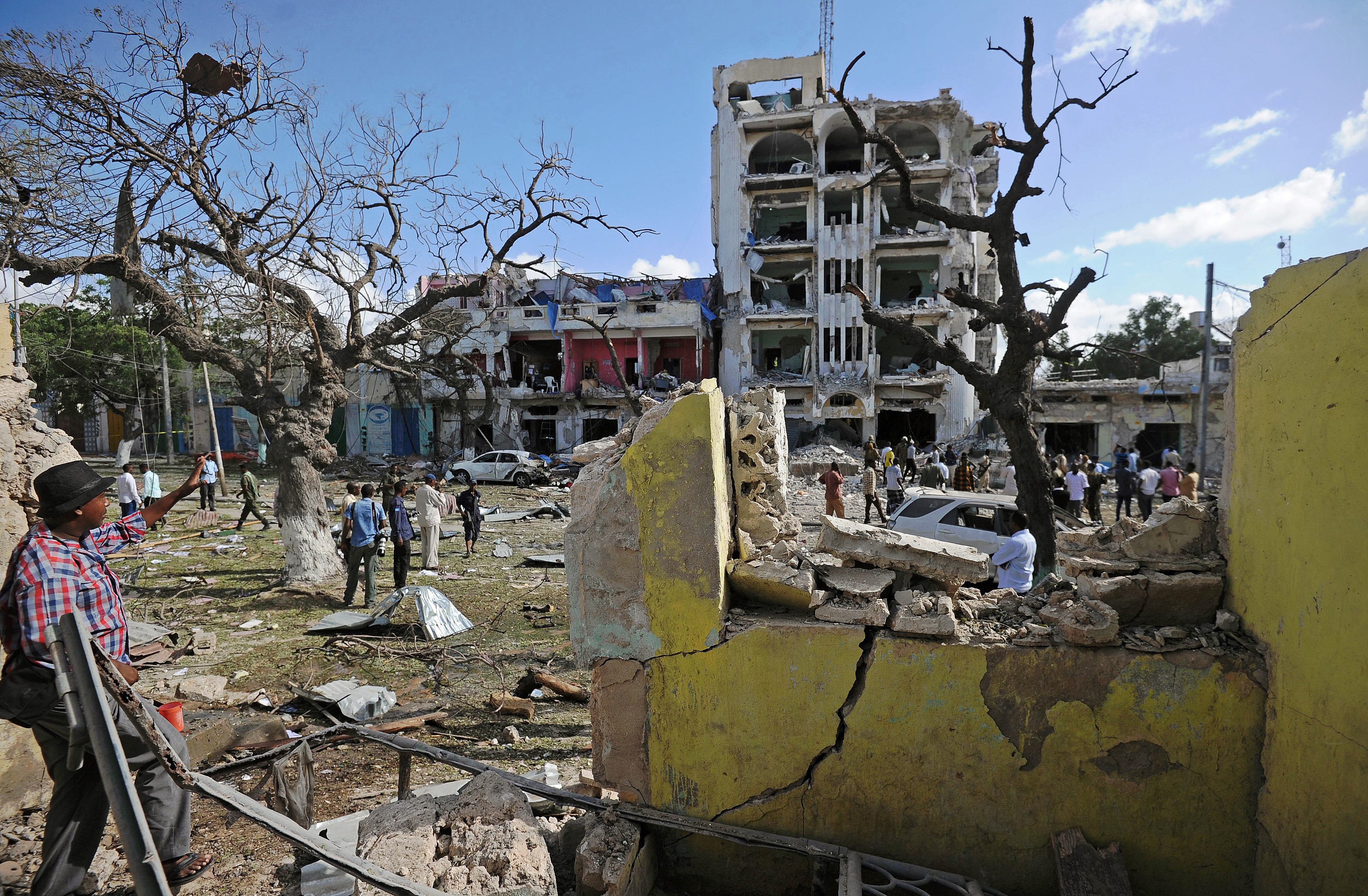 People stand on the scene of a terror attack outside The Ambassador Hotel in Mogadishu on June 2, 2016.