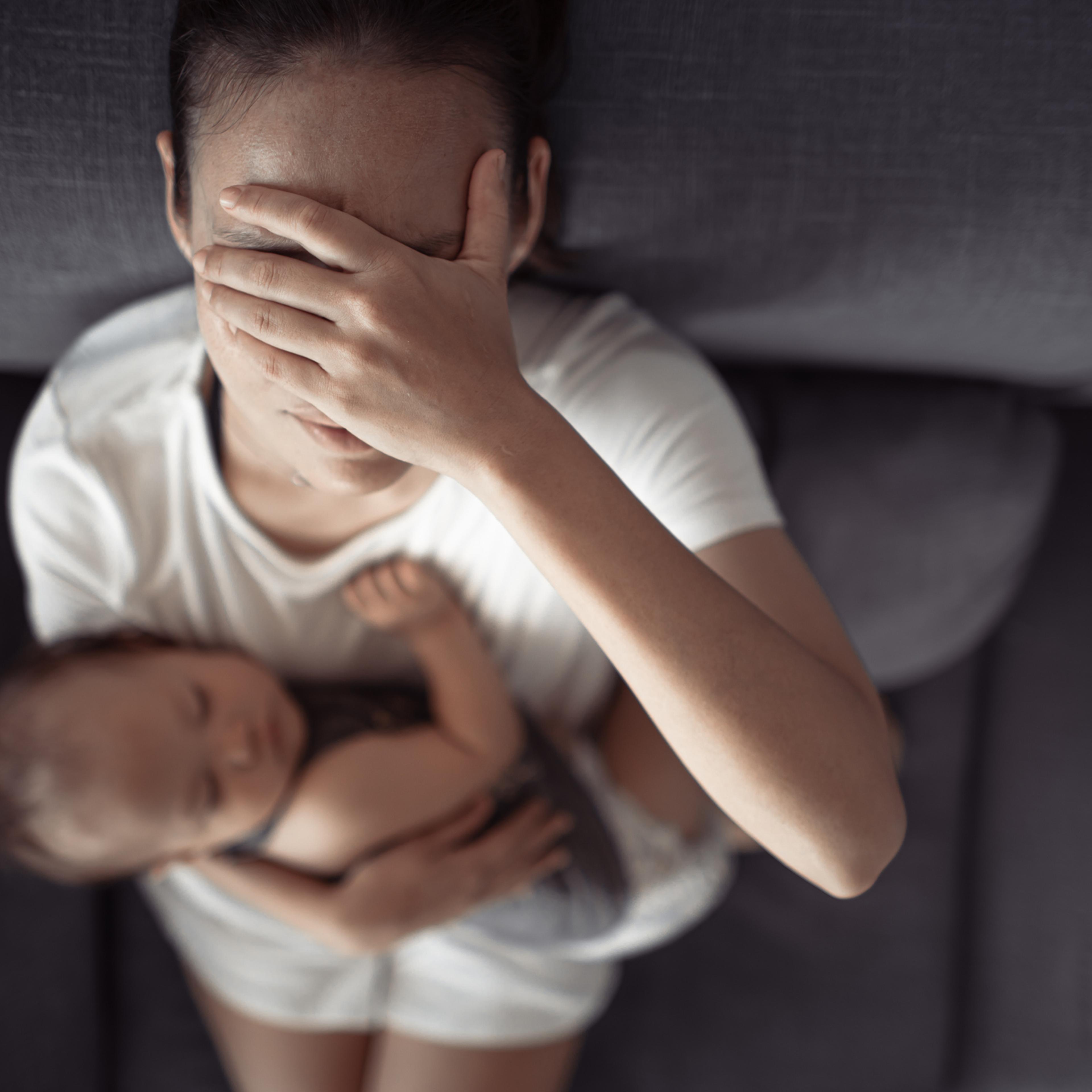 Tired mother having headache, stressed with baby child at home