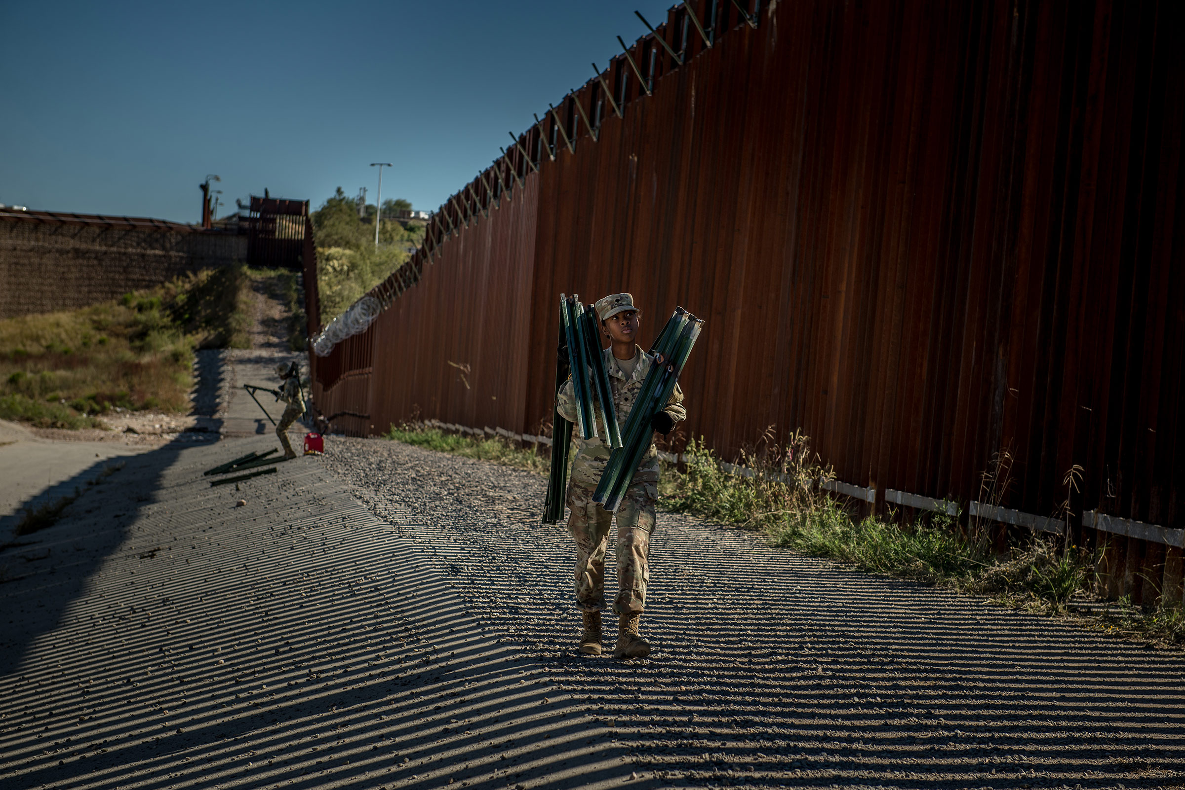 Soldiers install brackets and wire along the border wall in November.