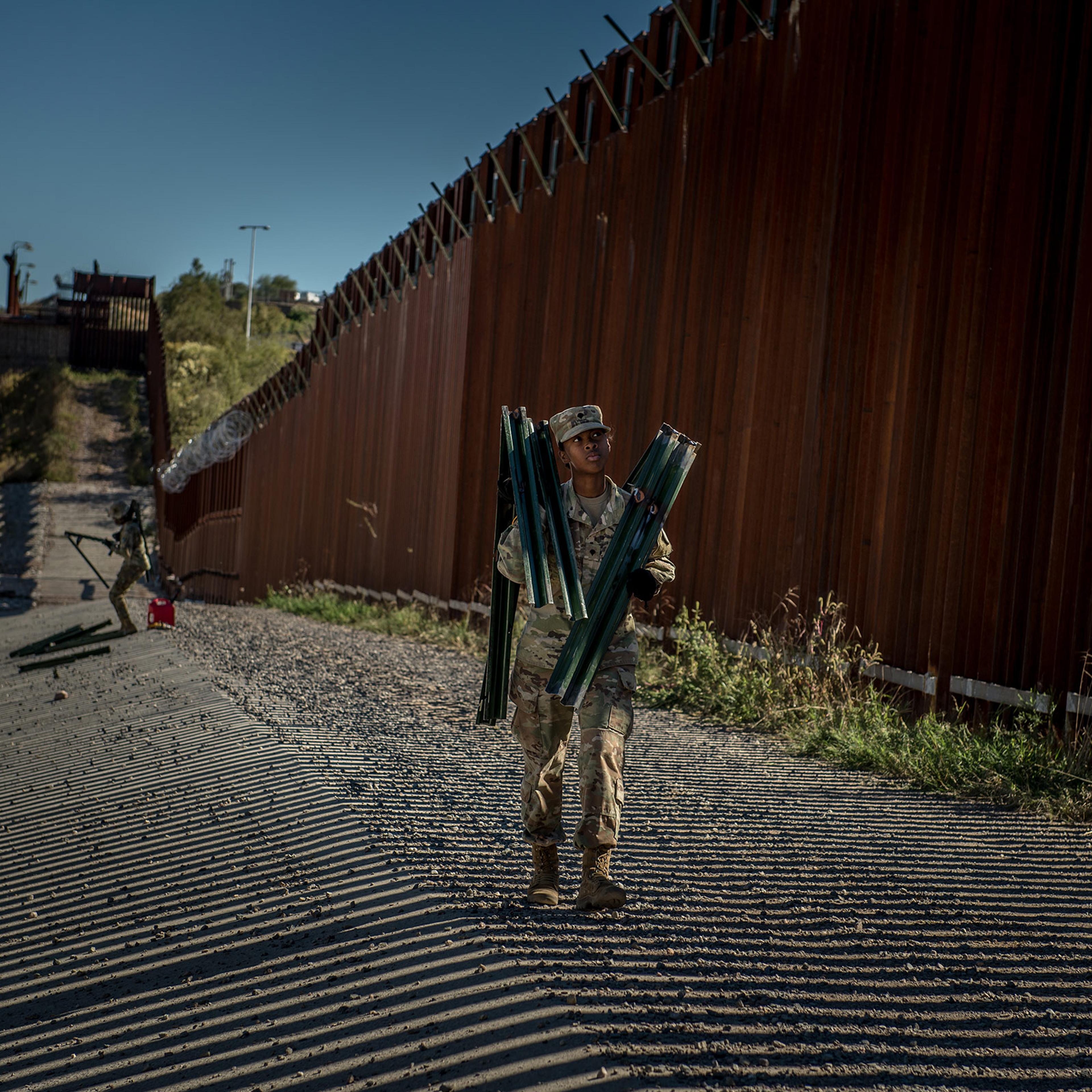 Soldiers install brackets and wire along the border wall in November.