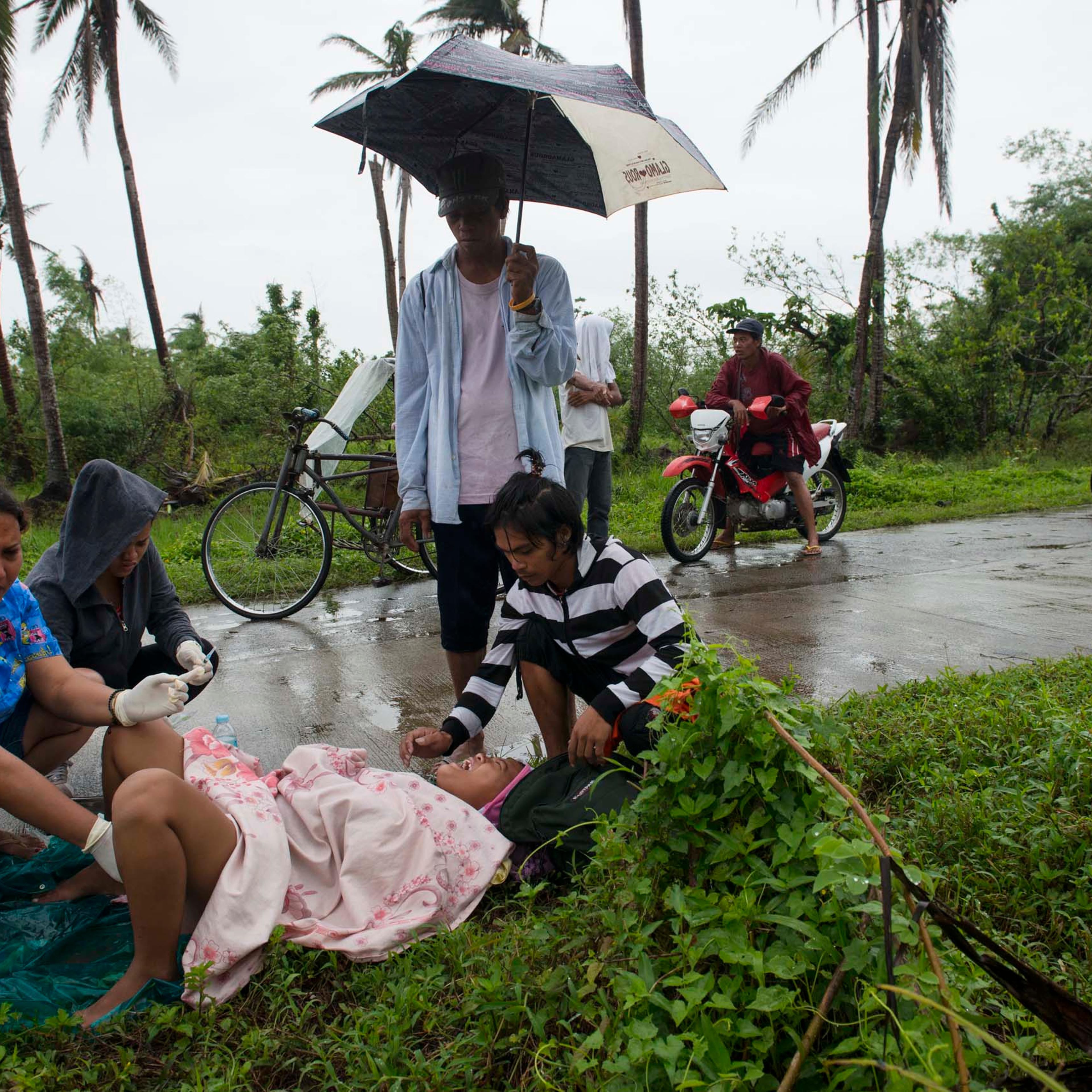Jan. 11, 2014: Midwife Norina Malate delivers the baby of Analyn Pesado, 18, as Analyn's partner, Ryan Bacate, 21, looks on at the side of the road en route to the nearest clinic in Tolosa, outside of Tacloban, in the Philippines.