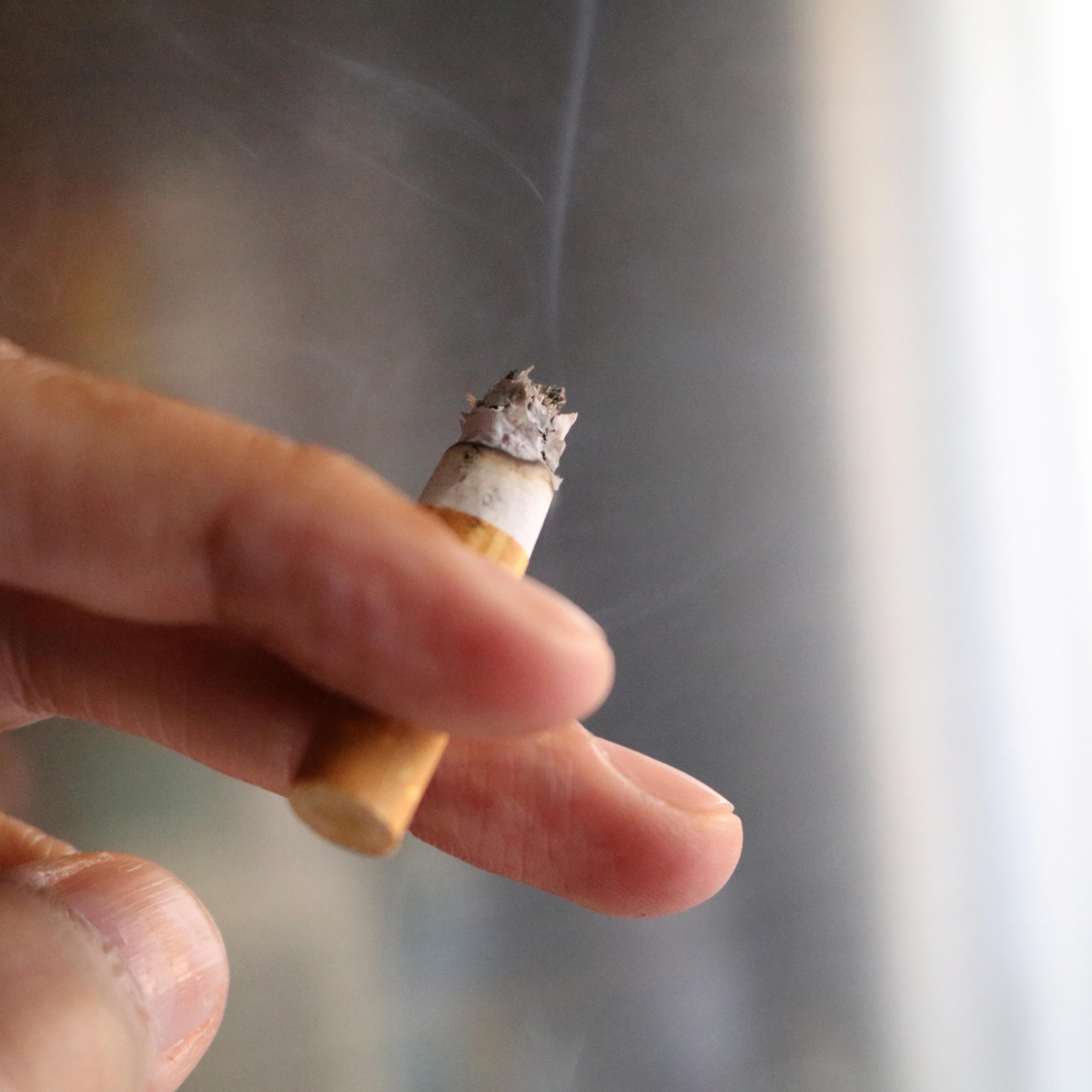 Cropped Image Of Hand Holding Burning Cigarette