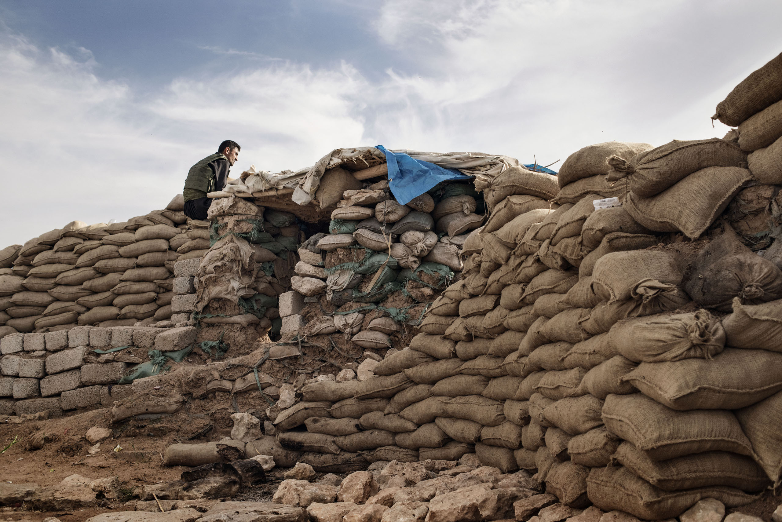 A member of the Kurdish Peshmerga armed forces sits atop sandbags, overlooking the ISIS-held city of Mosul, northern Iraq, May 9, 2016. The Kurdish fighters holding the line against ISIS are so close to ISIS positions that they can even pick up the jihad