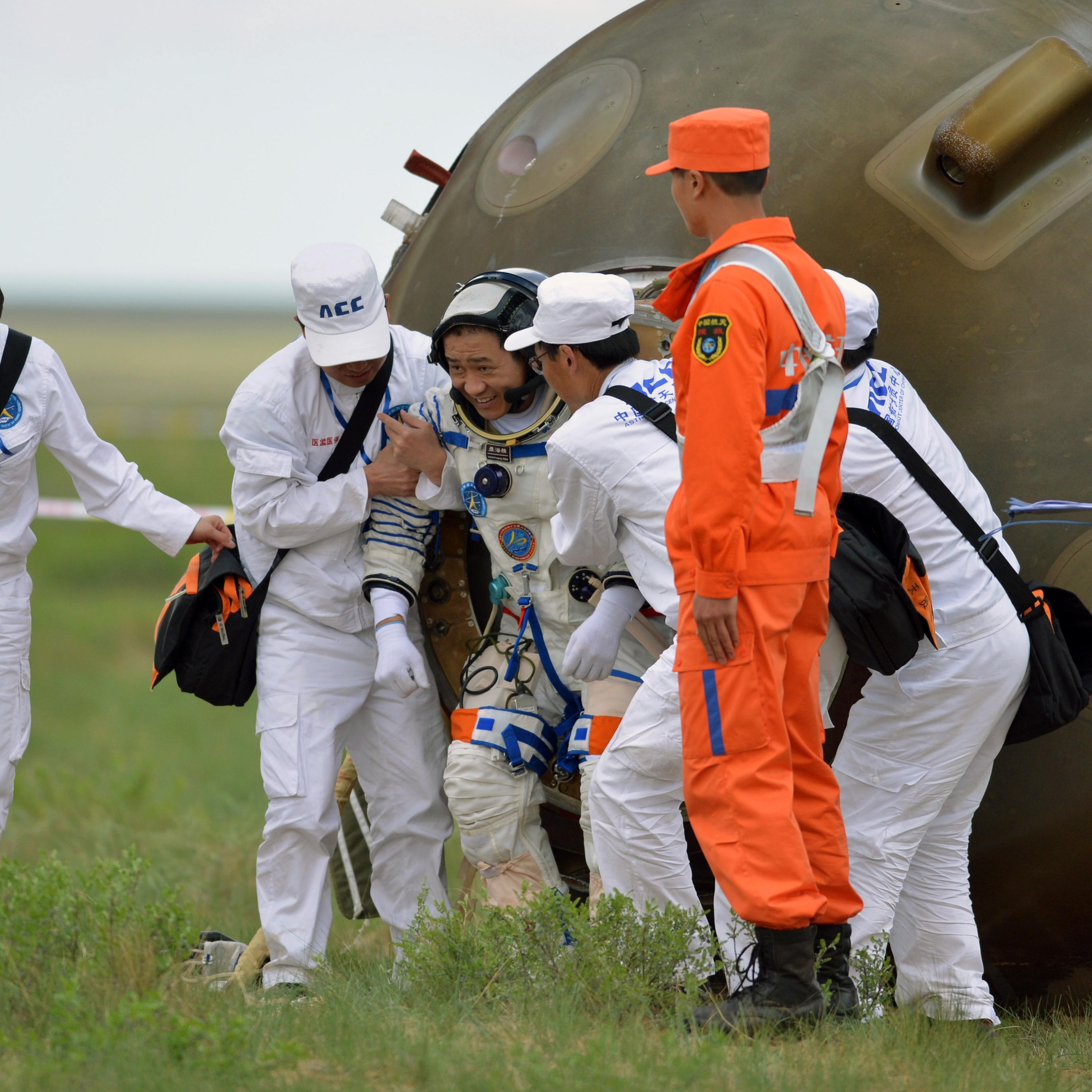 Welcome home: Nie Haisheng is helped out of his Shenzhou 10 spacecraft after a 15-day mission in 2013.