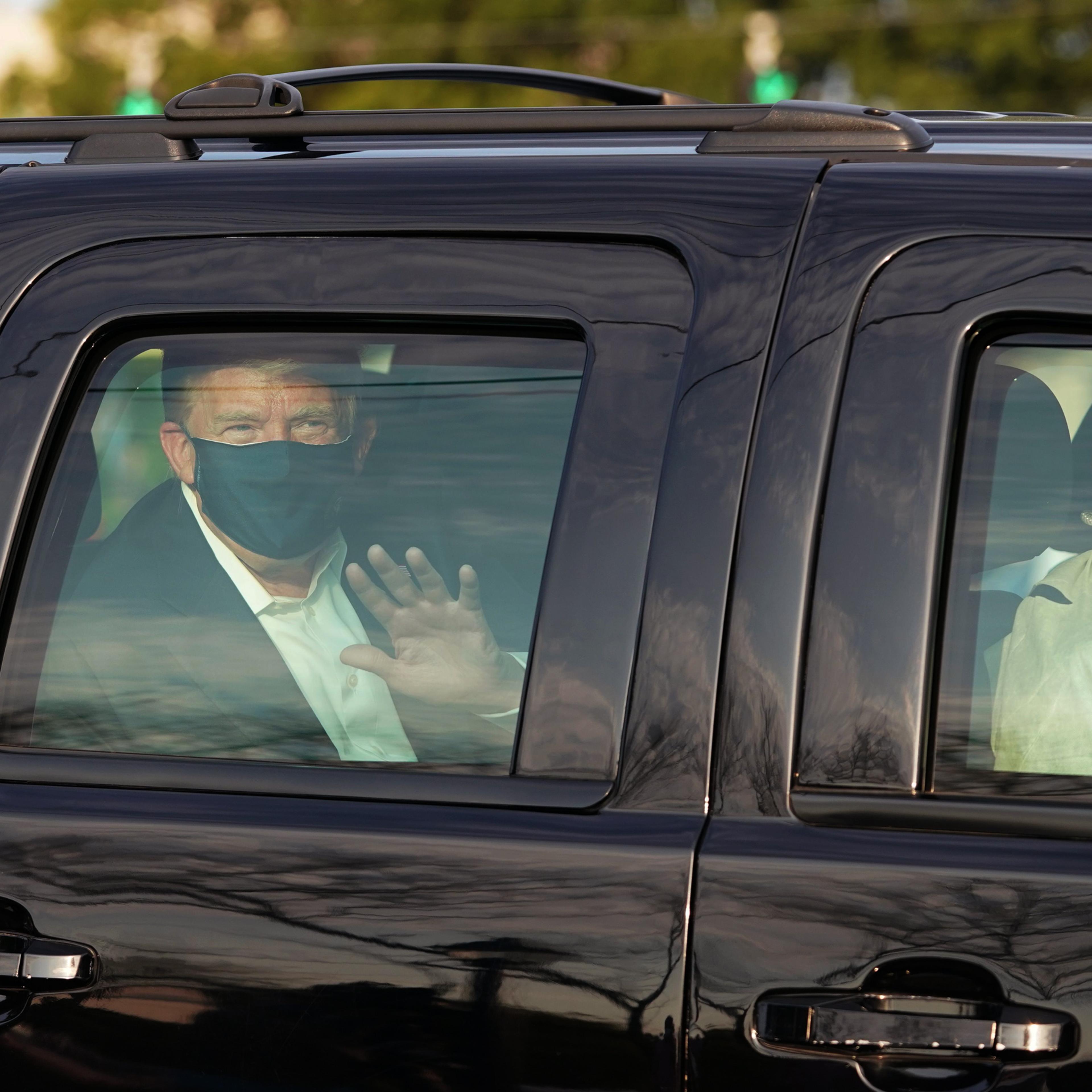 President Trump waves from the back of an SUV in a motorcade outside of Walter Reed in Bethesda, Md., on Oct. 4, 2020.