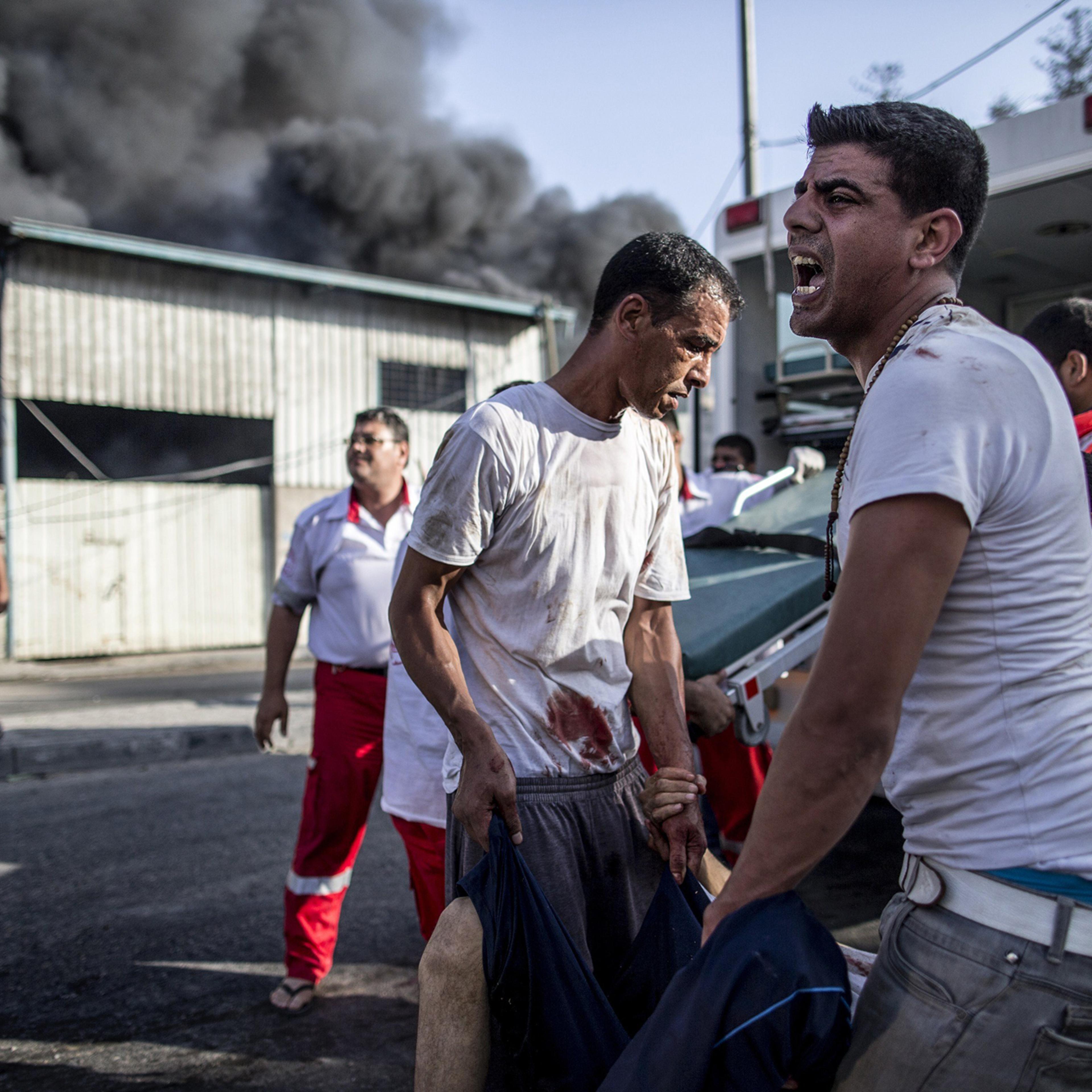 Palestinian emergency personnel and civilians evacuate victims of an Israeli air strike on a market place in the Shejaiya neighborhood near Gaza City, on July 30, 2014.