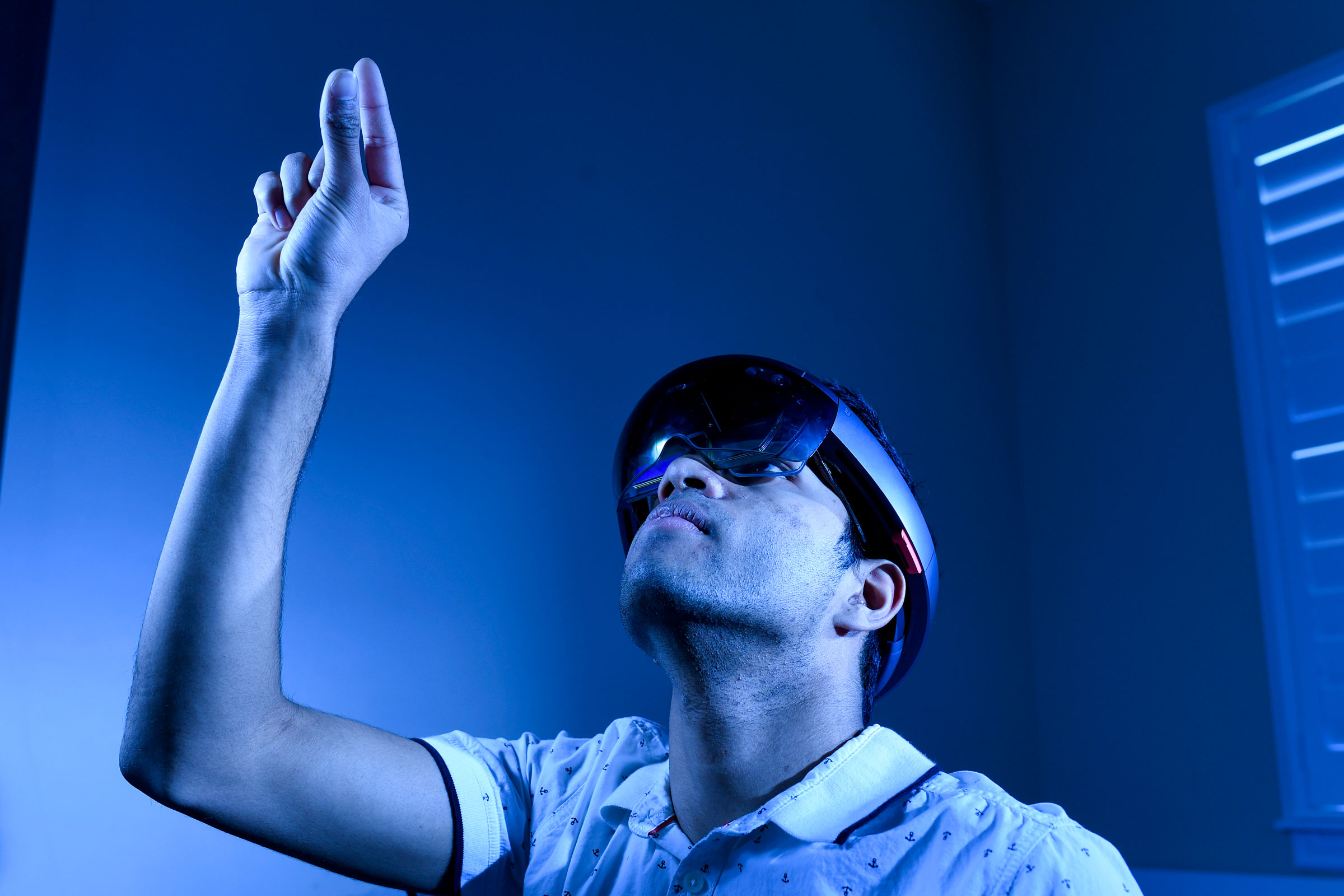 Krithik Ramesh, winner of the Intel International Science and Engineering Fair posing for a photo in his home, while using his program that overlays a 3d skeletal diagram over patients and can by controlled with hand movement