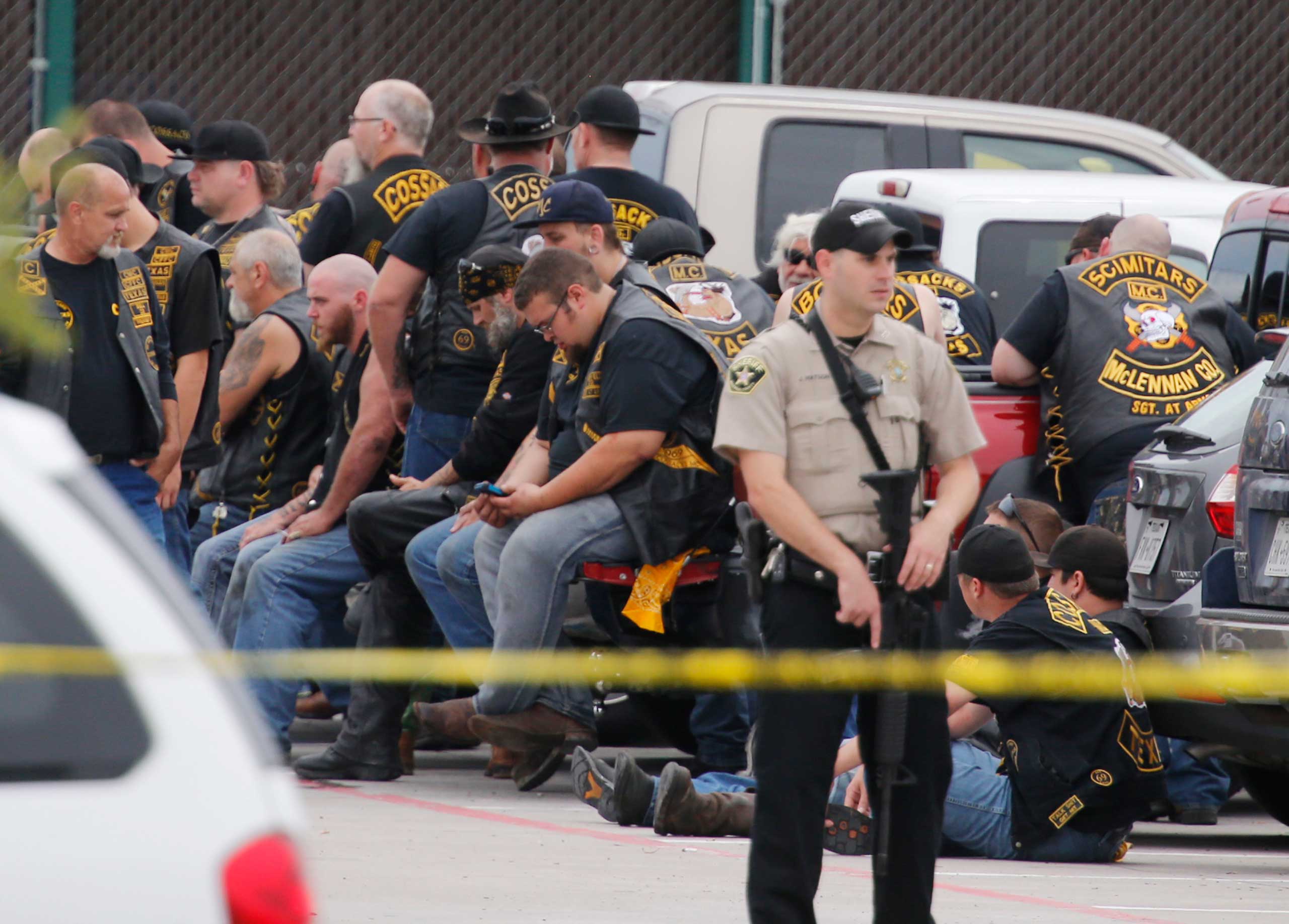 A McLennan County deputy stands guard near a group of bikers in the parking lot of a Twin Peaks restaurant Sunday, May 17, 2015, in Waco, Texas. Waco Police Sgt. W. Patrick Swanton told KWTX-TV there were "multiple victims" after gunfire erupted between 