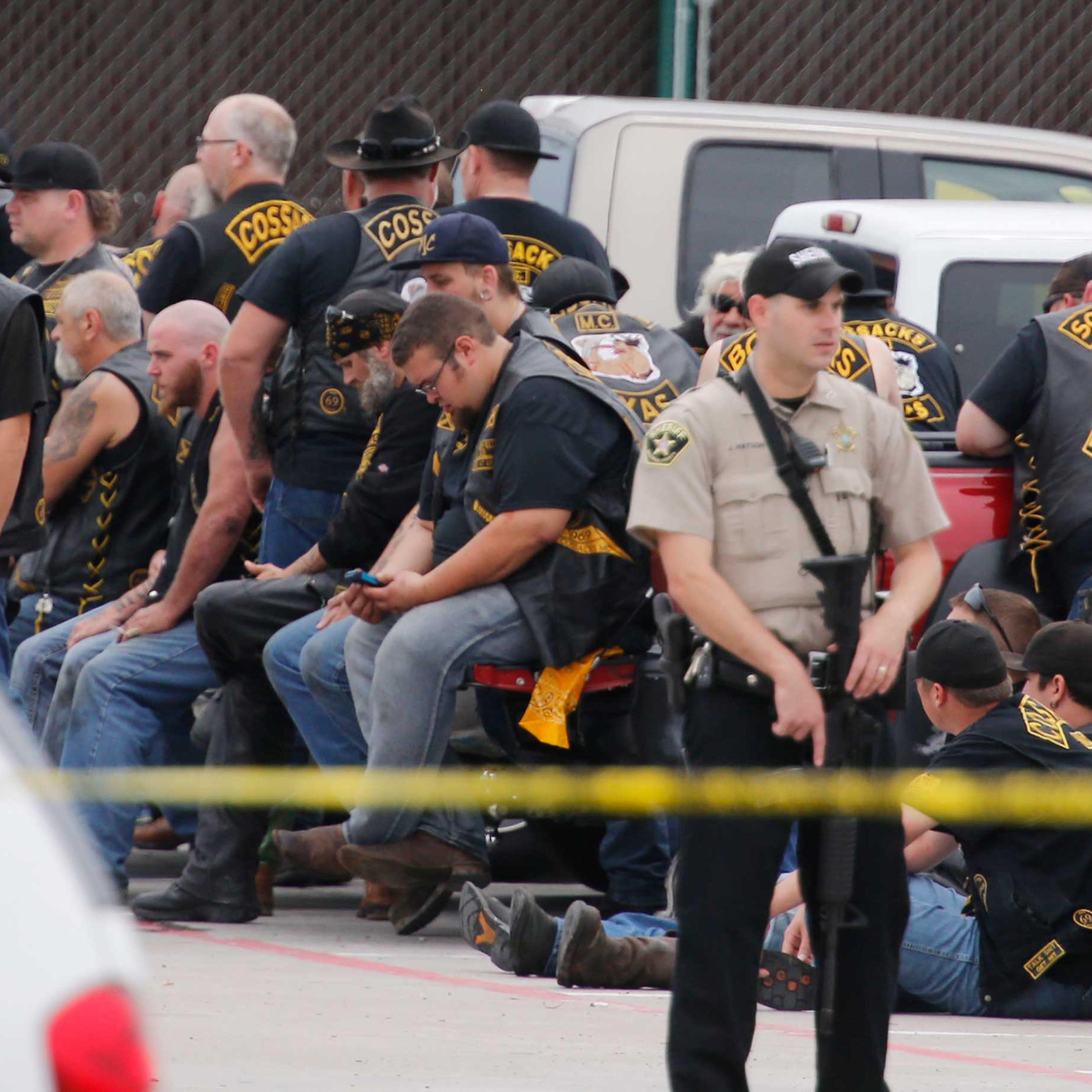 A McLennan County deputy stands guard near a group of bikers in the parking lot of a Twin Peaks restaurant Sunday, May 17, 2015, in Waco, Texas. Waco Police Sgt. W. Patrick Swanton told KWTX-TV there were "multiple victims" after gunfire erupted between