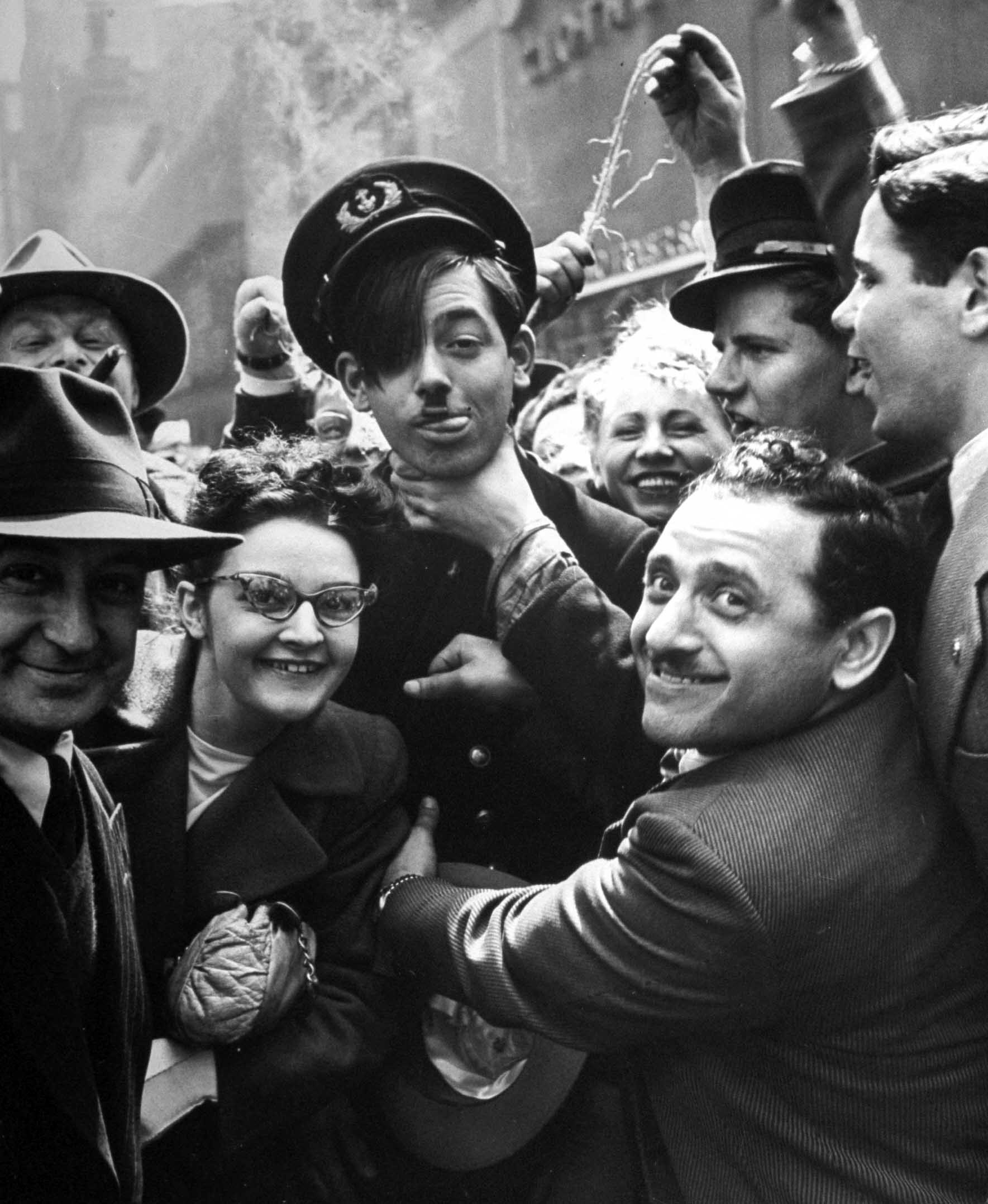 A "Hitler," who is really Bill Eckert of Merchant Marine with hair over his eyes, is throttled by celebrating passers-by.