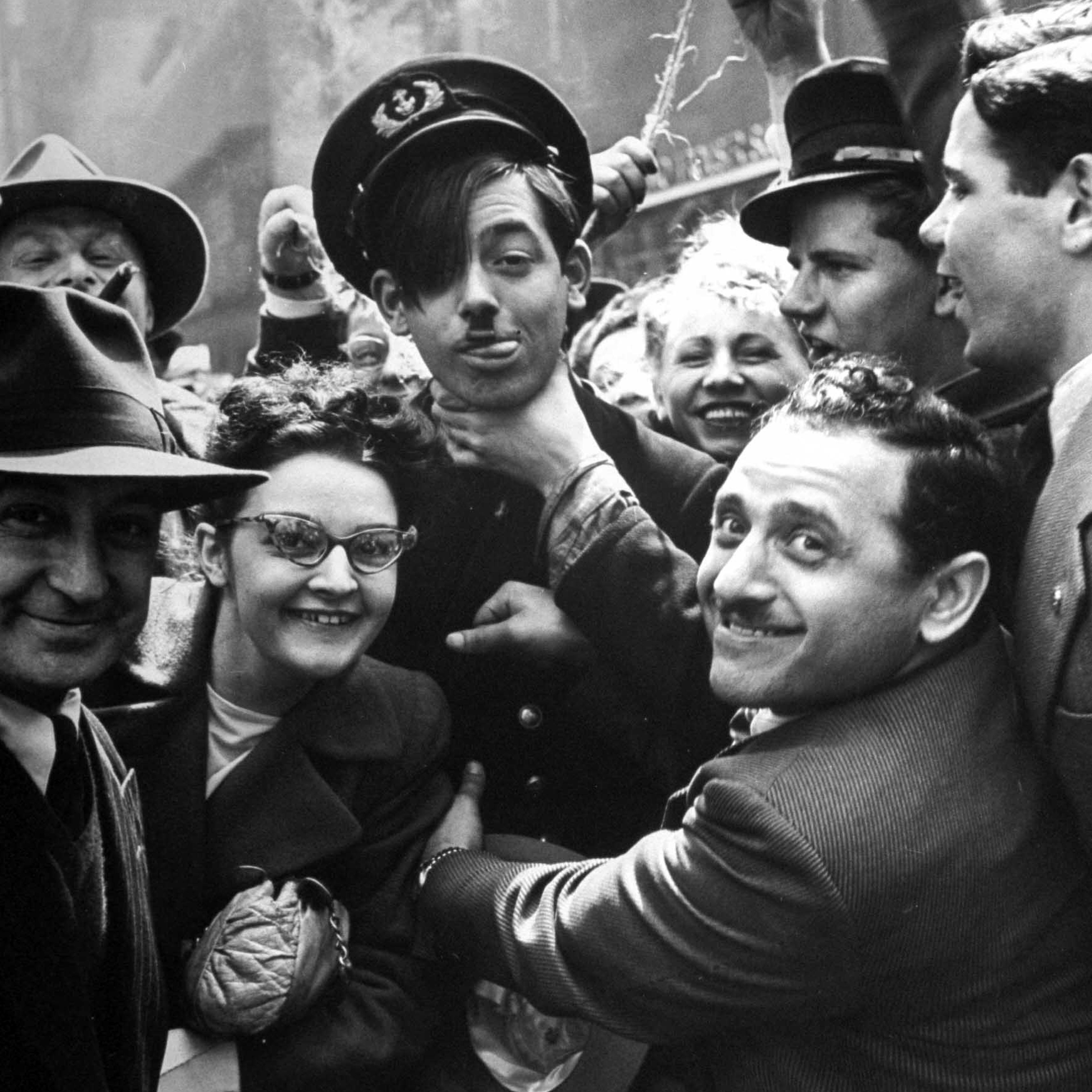 A "Hitler," who is really Bill Eckert of Merchant Marine with hair over his eyes, is throttled by celebrating passers-by.