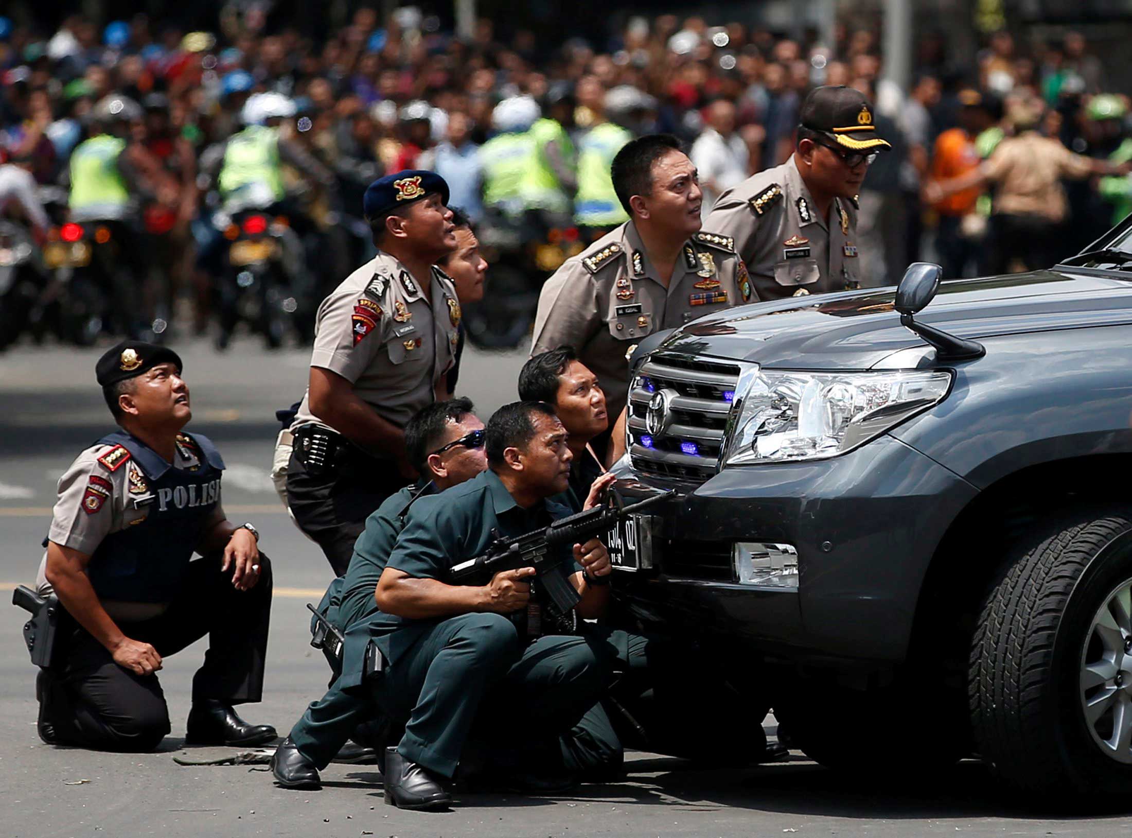 Police officers react near the site of a blast in Jakarta, Indonesia, Jan.14, 2016.