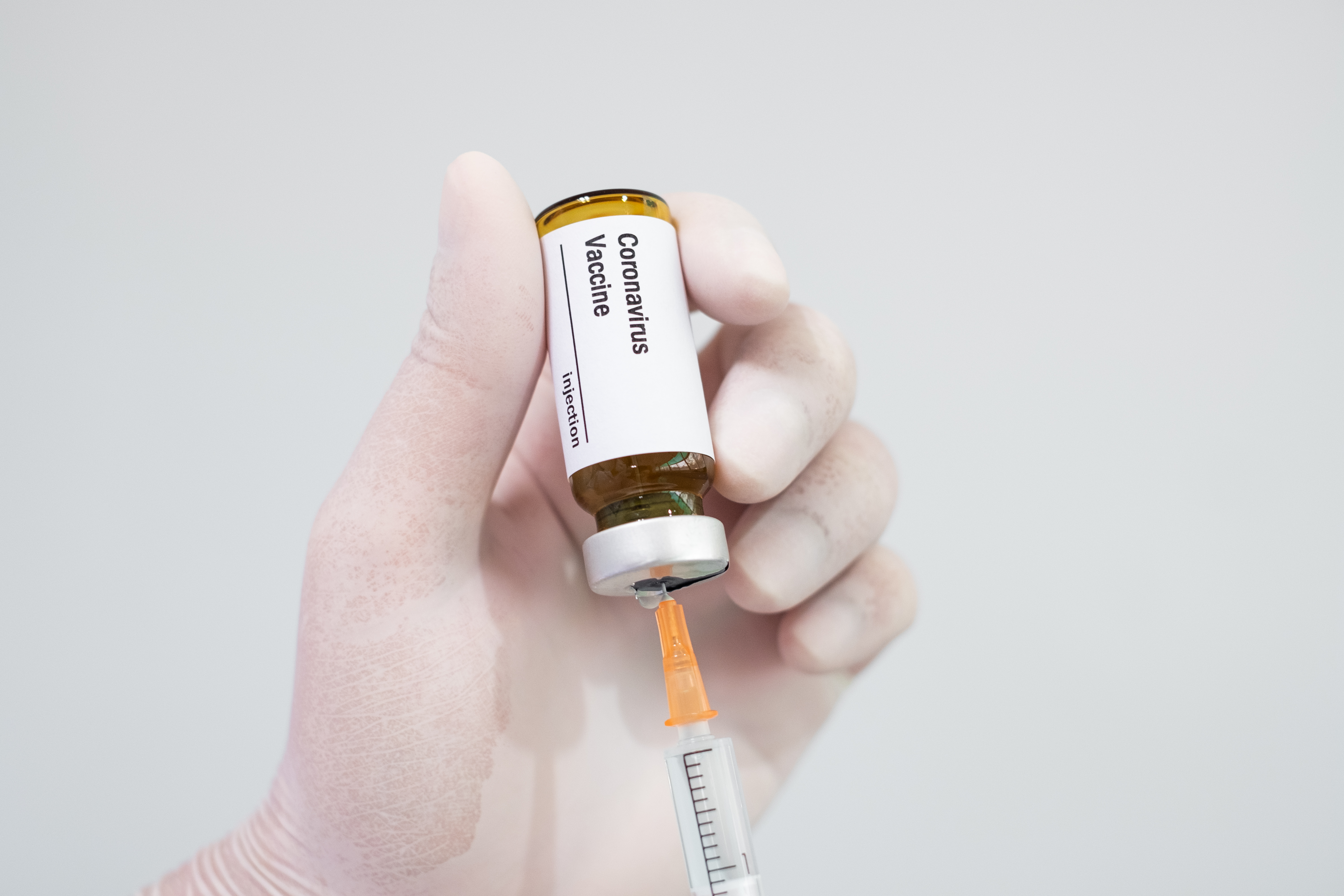 Doctor's hand holding a syringe of covid-19 vaccine and vaccine vial