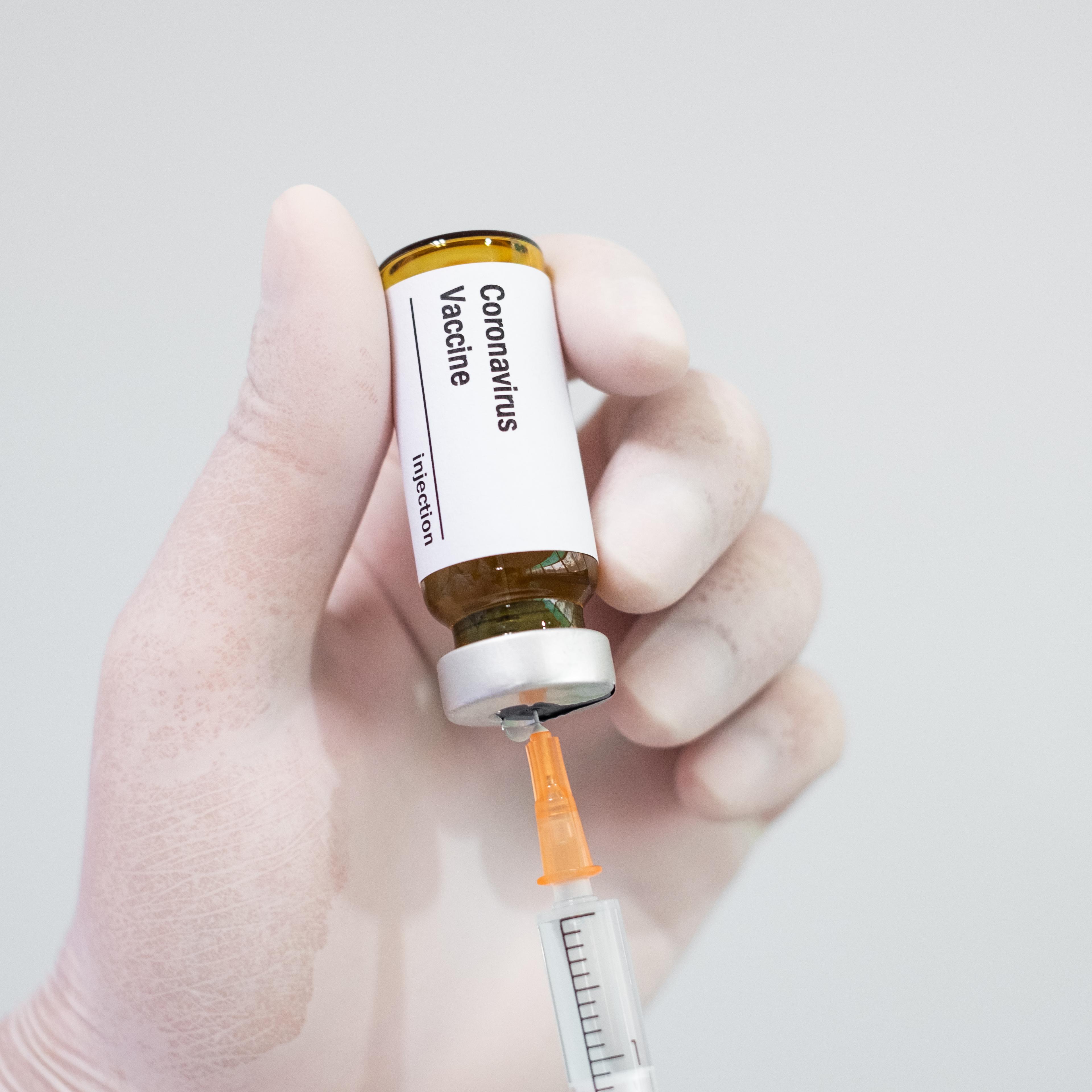 Doctor's hand holding a syringe of covid-19 vaccine and vaccine vial
